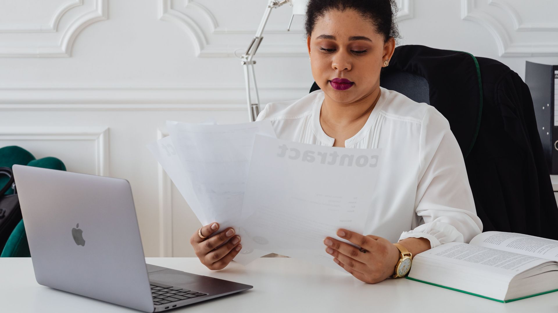 Confident businesswoman analyzing contracts at her clean, organized desk.