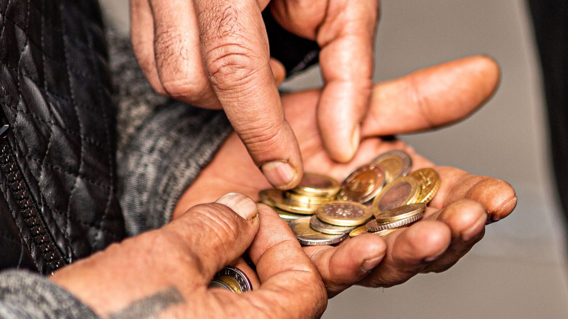 Detailed shot of hands exchanging coins, illustrating financial transactions.