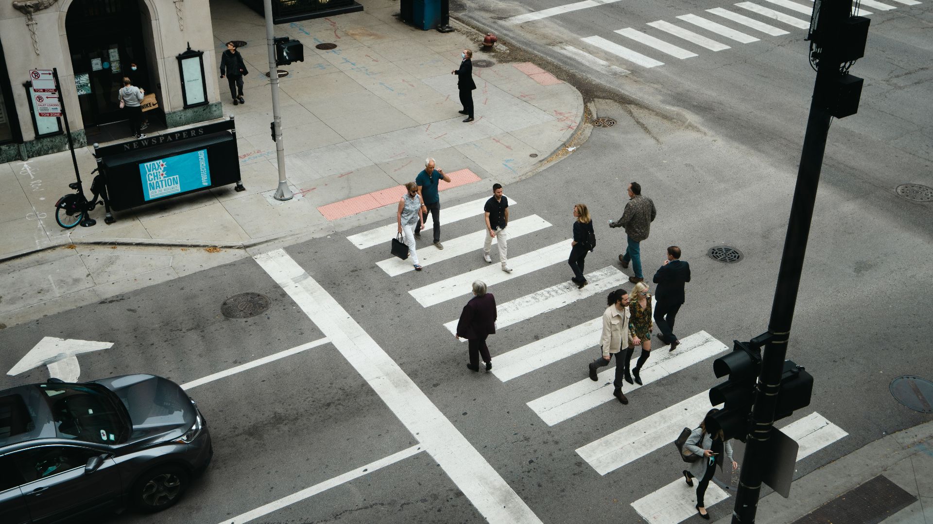Aerial view of people crossing a city street at a pedestrian crosswalk.