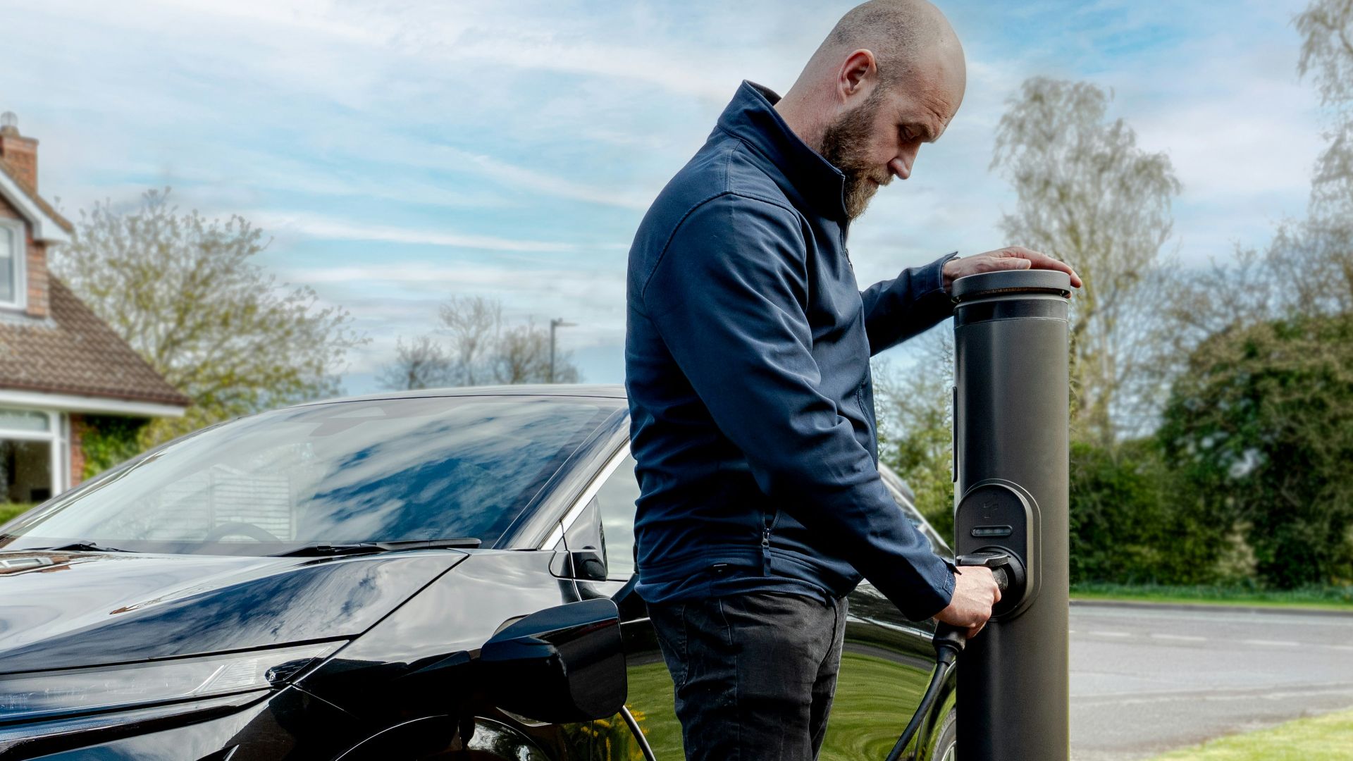 Man charging an electric car at an outdoor station