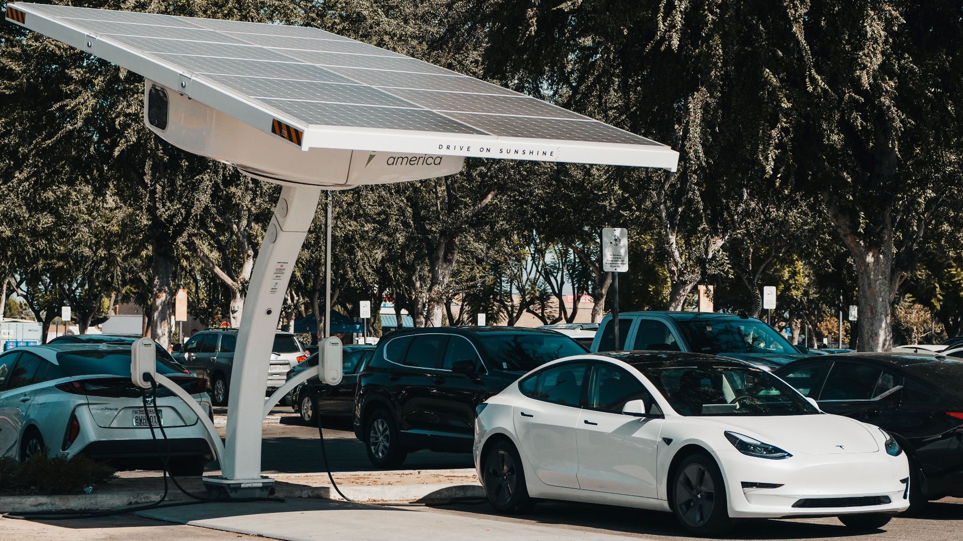Electric car parked at a solar charging station outdoors, highlighting renewable energy and innovation.
