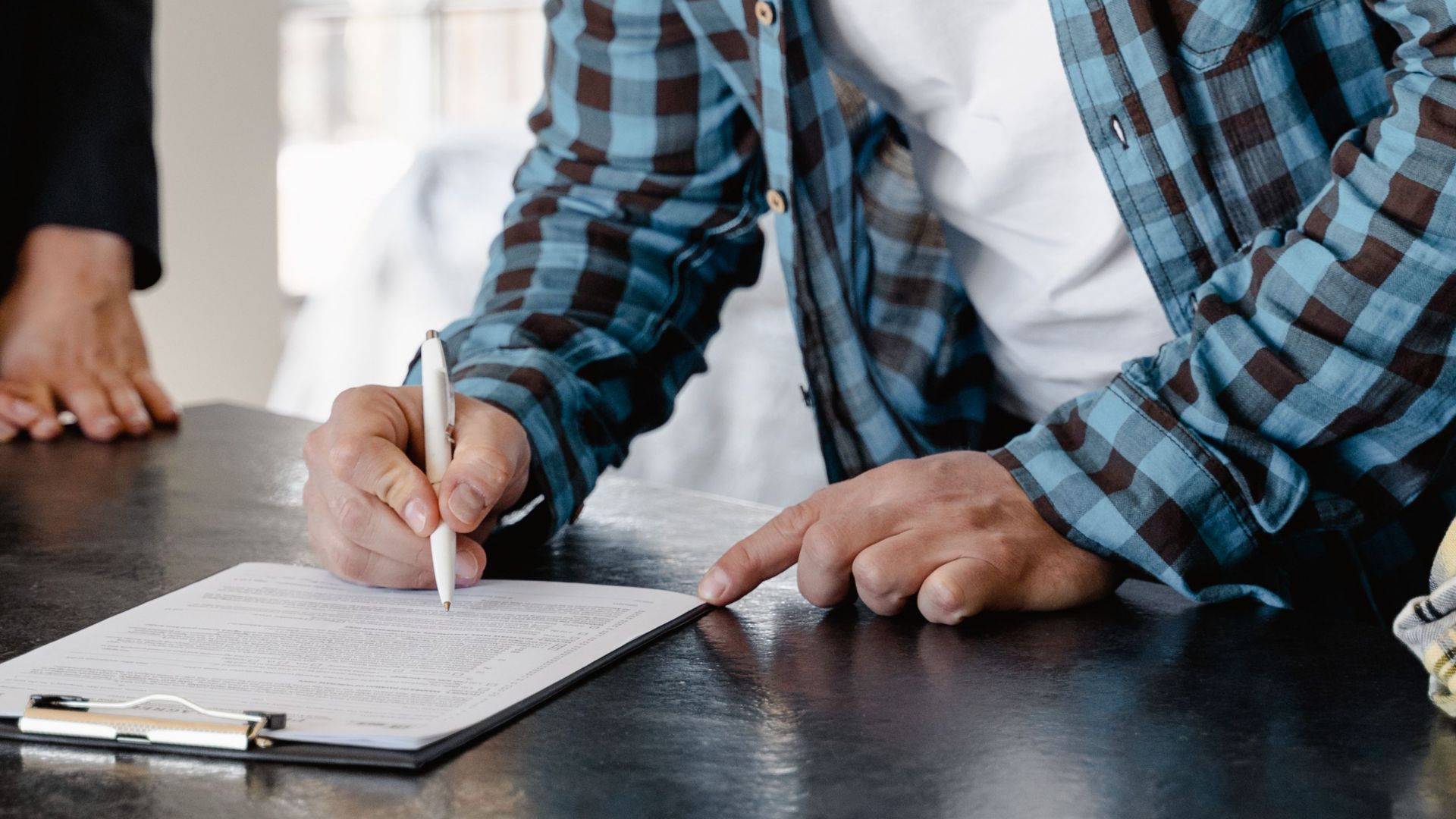 A man signs important papers in a stylish home setting, symbolizing a new start.