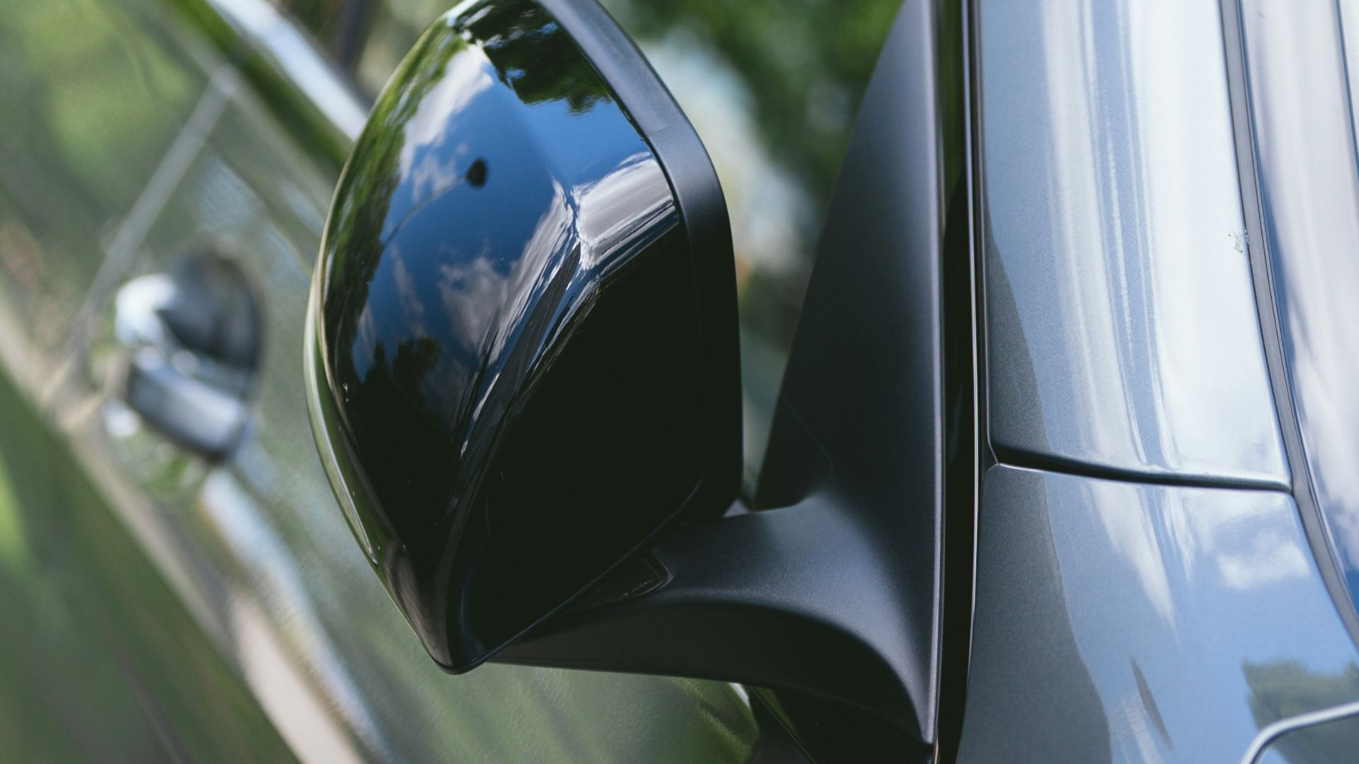 Close-up of a car's side mirror reflecting trees