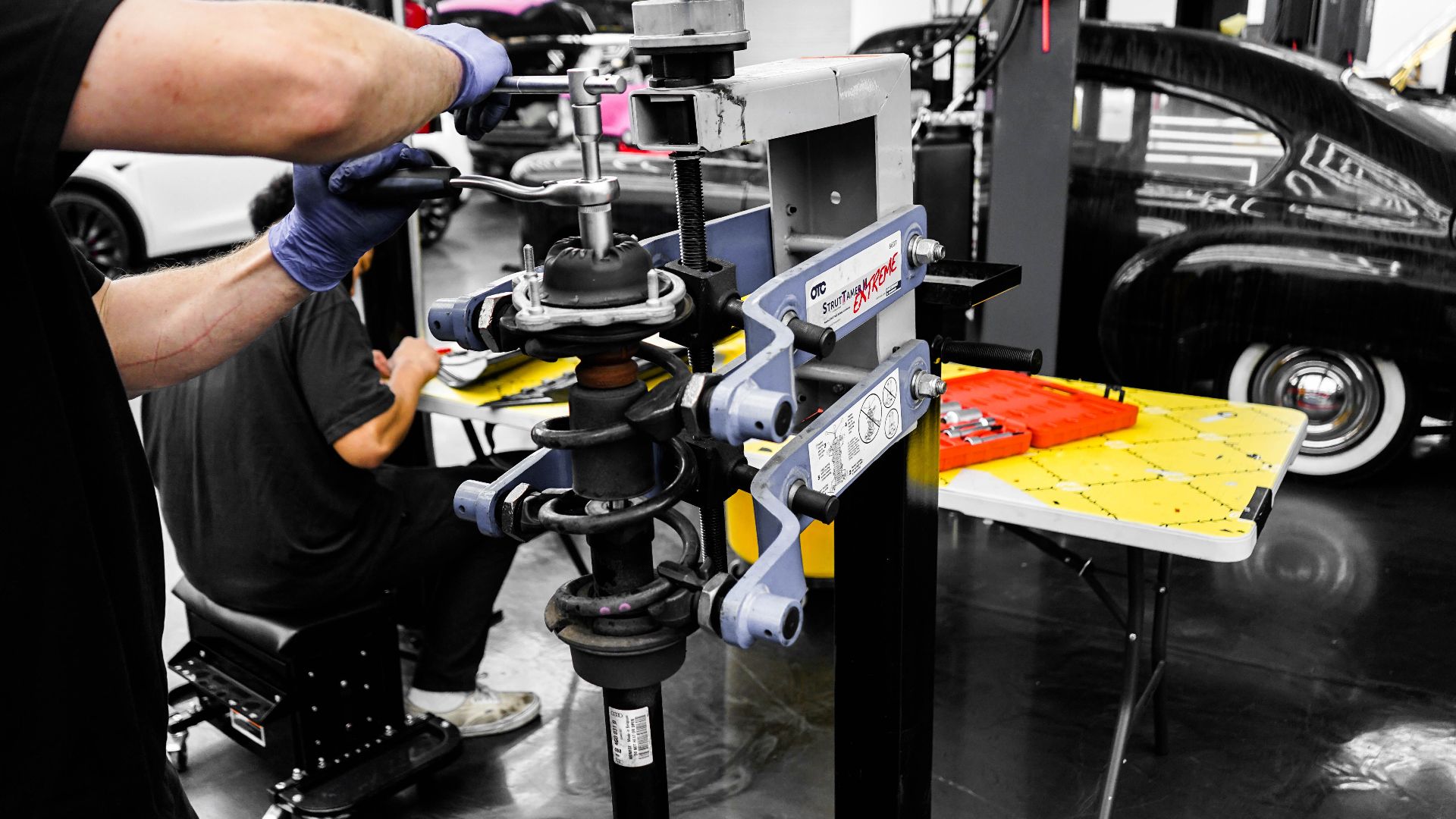 Mechanics using specialized equipment to repair vehicles in an automotive workshop.