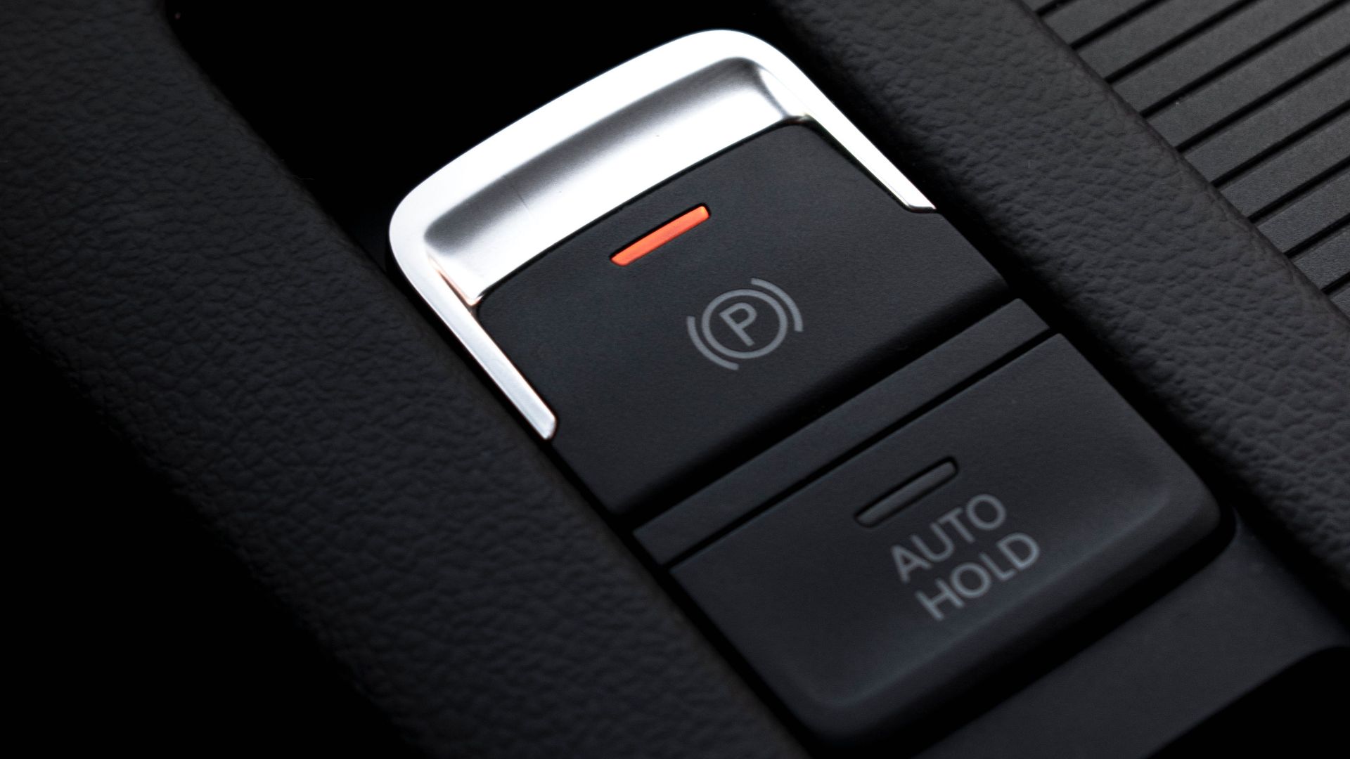 Detailed view of an electronic parking brake and auto hold button in a vehicle interior.