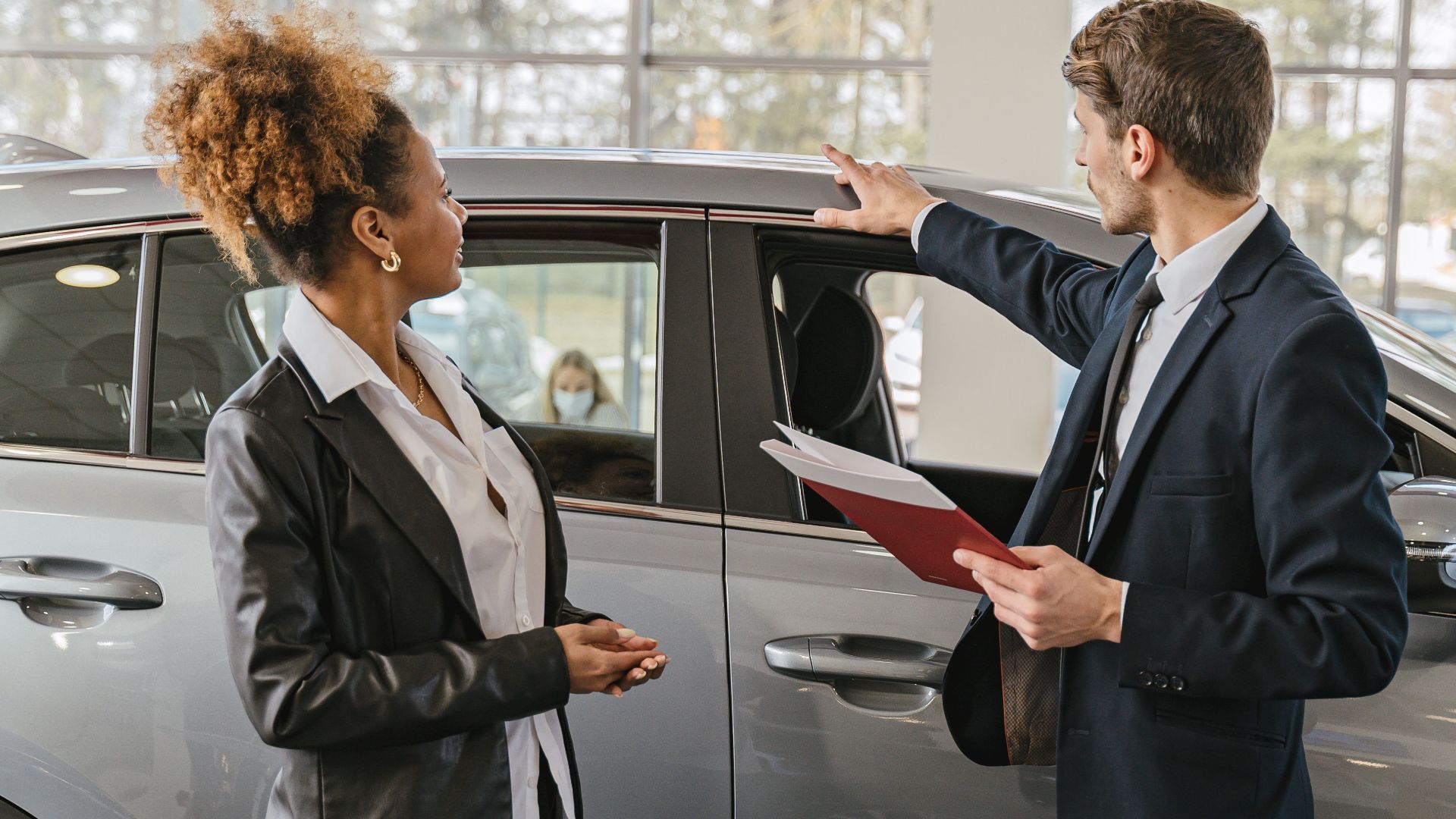 A woman and a car salesman discuss vehicle options inside a dealership.