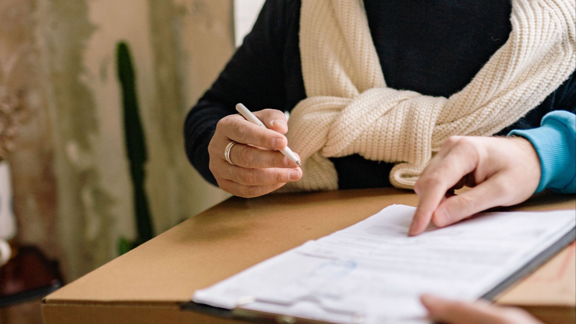 A person receives a package with a document and wears a medical mask indoors.