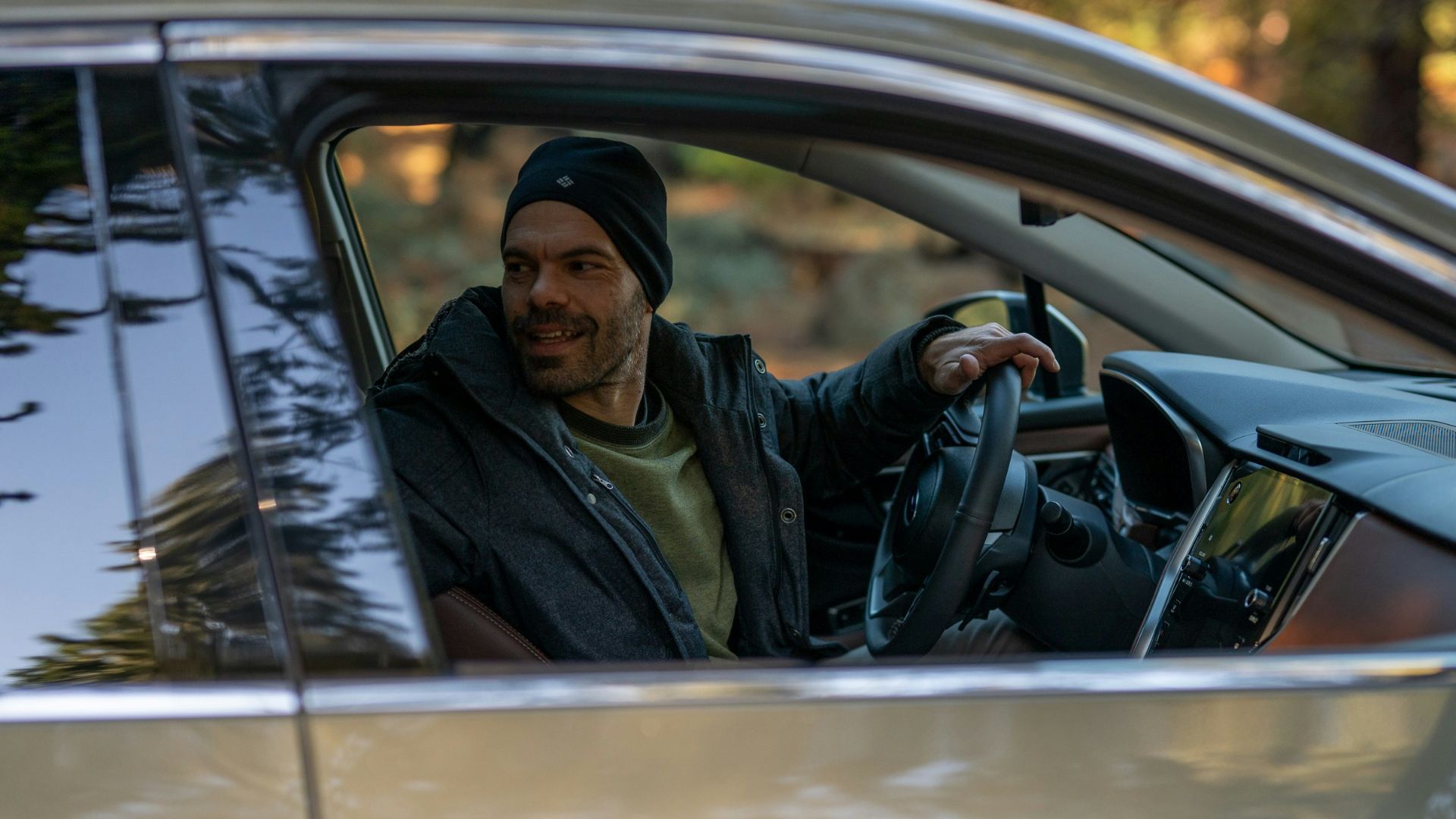 A man sitting in a car holding a steering wheel
