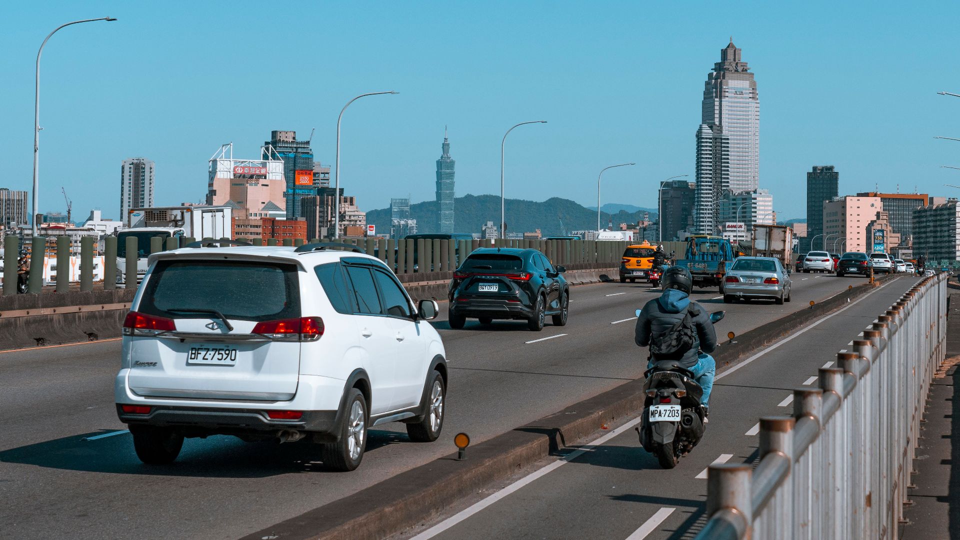 Busy urban scene showcasing traffic on a bridge with city skyscrapers in the background.