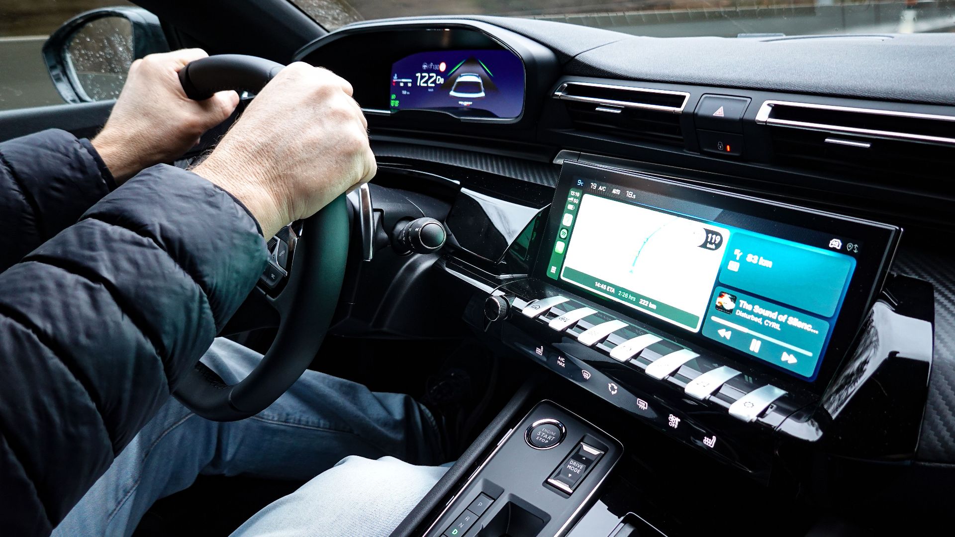 A detailed view of a car's interior with hands on the steering wheel, showcasing modern technology.