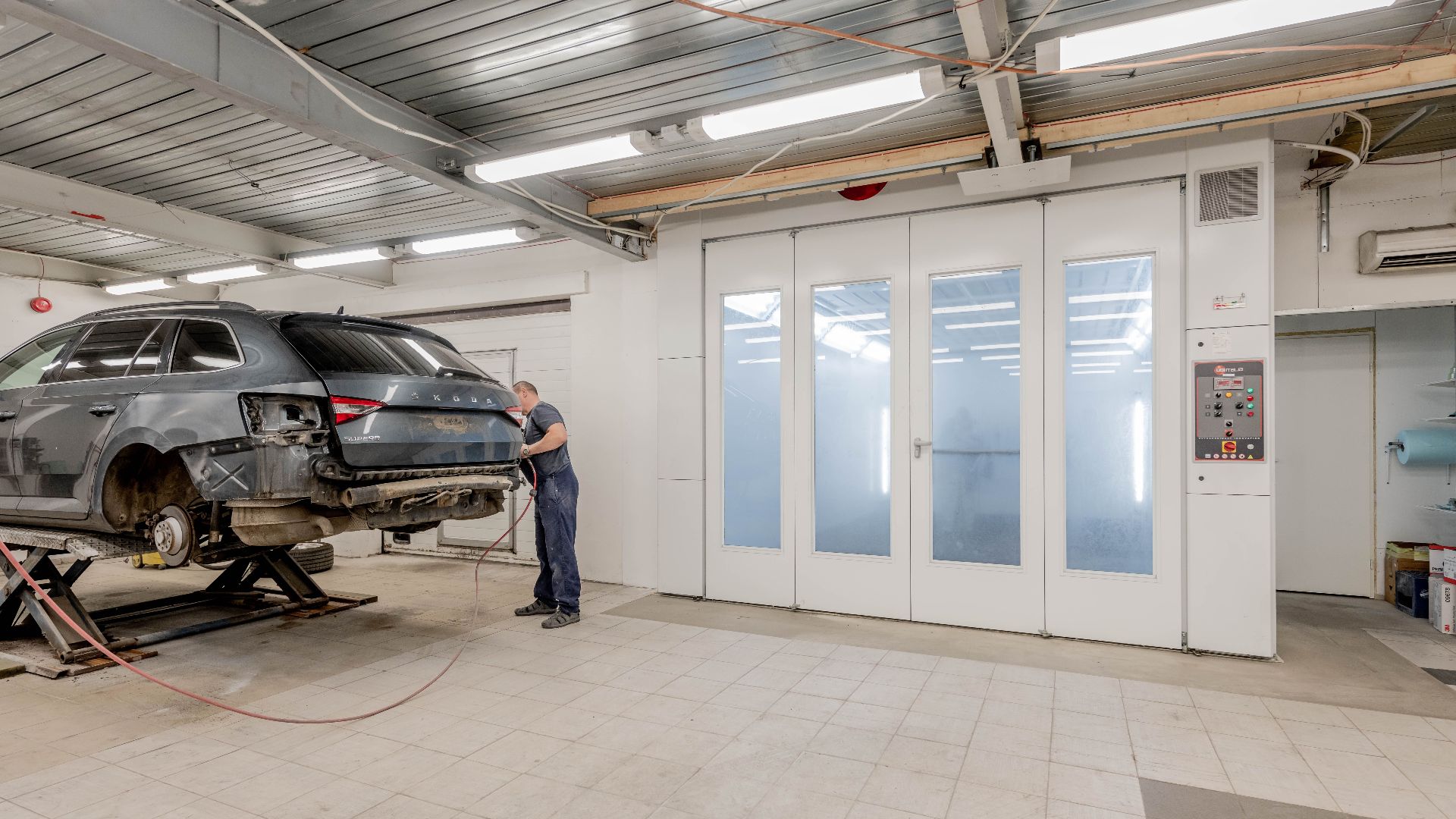 Mechanic repairing a car indoors at an auto workshop, focusing on vehicle maintenance.