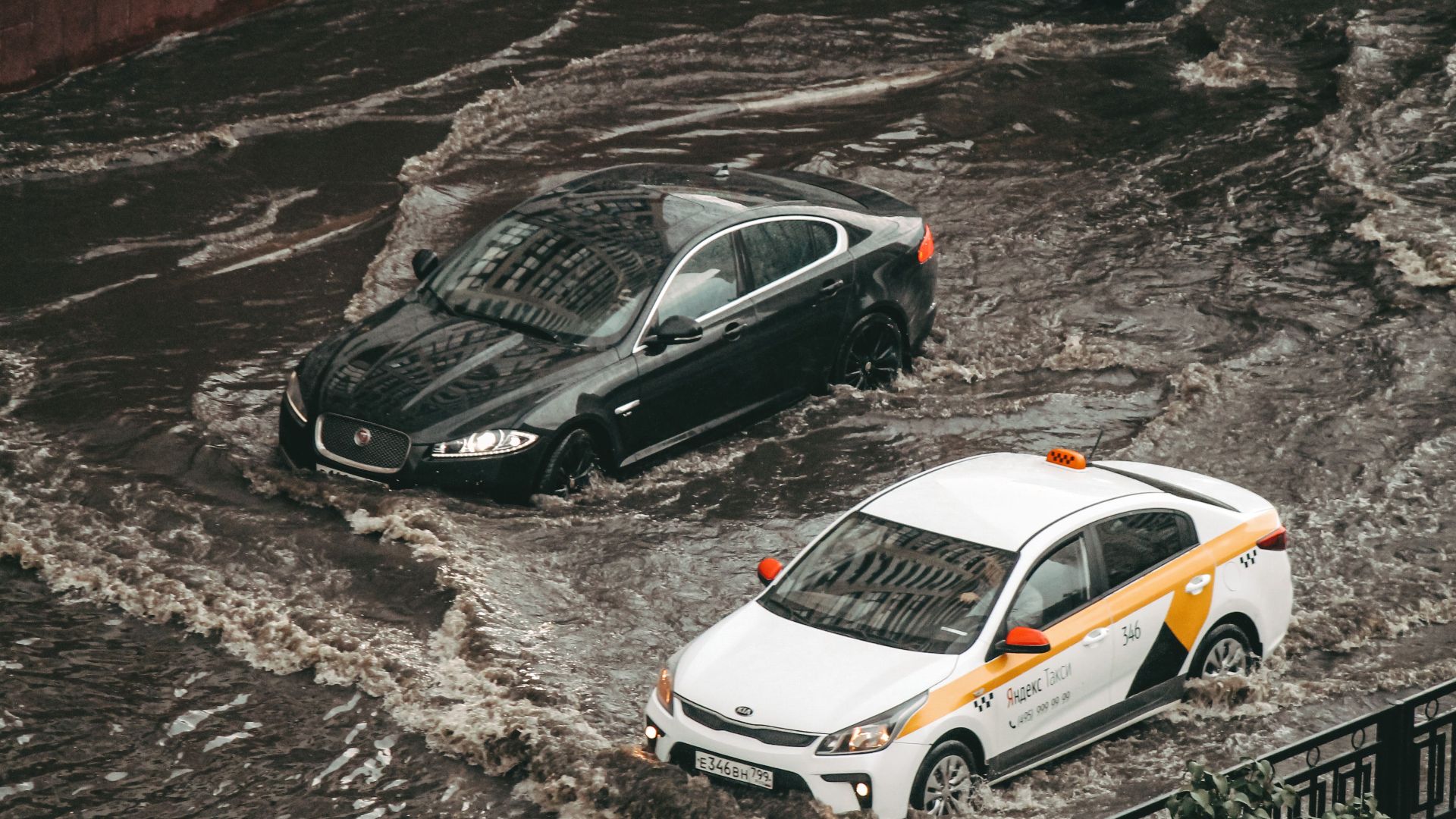 Cars navigating through a flooded city street, showcasing urban chaos and weather impacts.