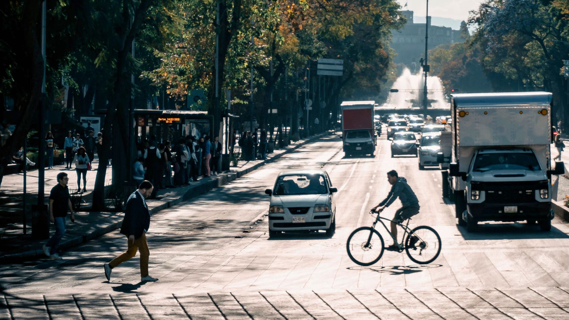 Busy city street in Mexico City featuring cyclists, pedestrians, and traffic under clear skies.