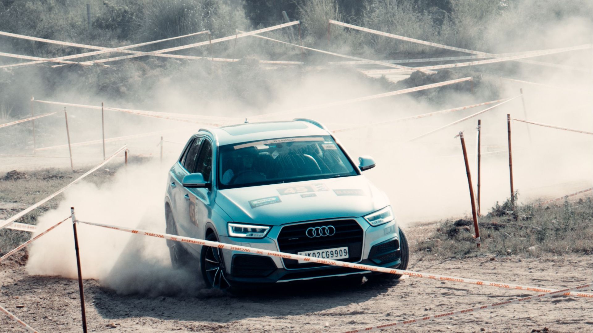 Dynamic shot of an Audi SUV racing on a dusty track in Jammu, showcasing its power and agility.