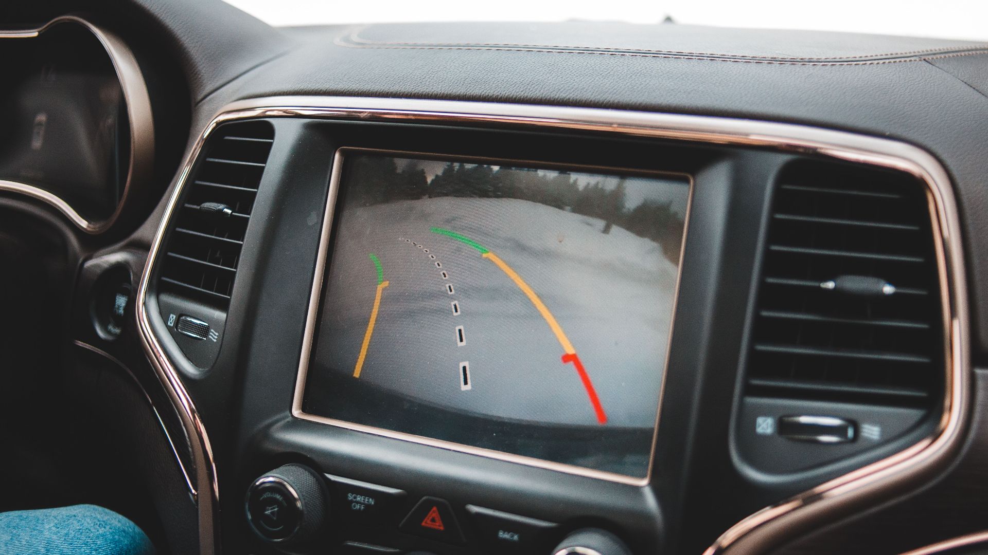 Close-up of a car's dashboard showing a rearview camera display for parking assistance.