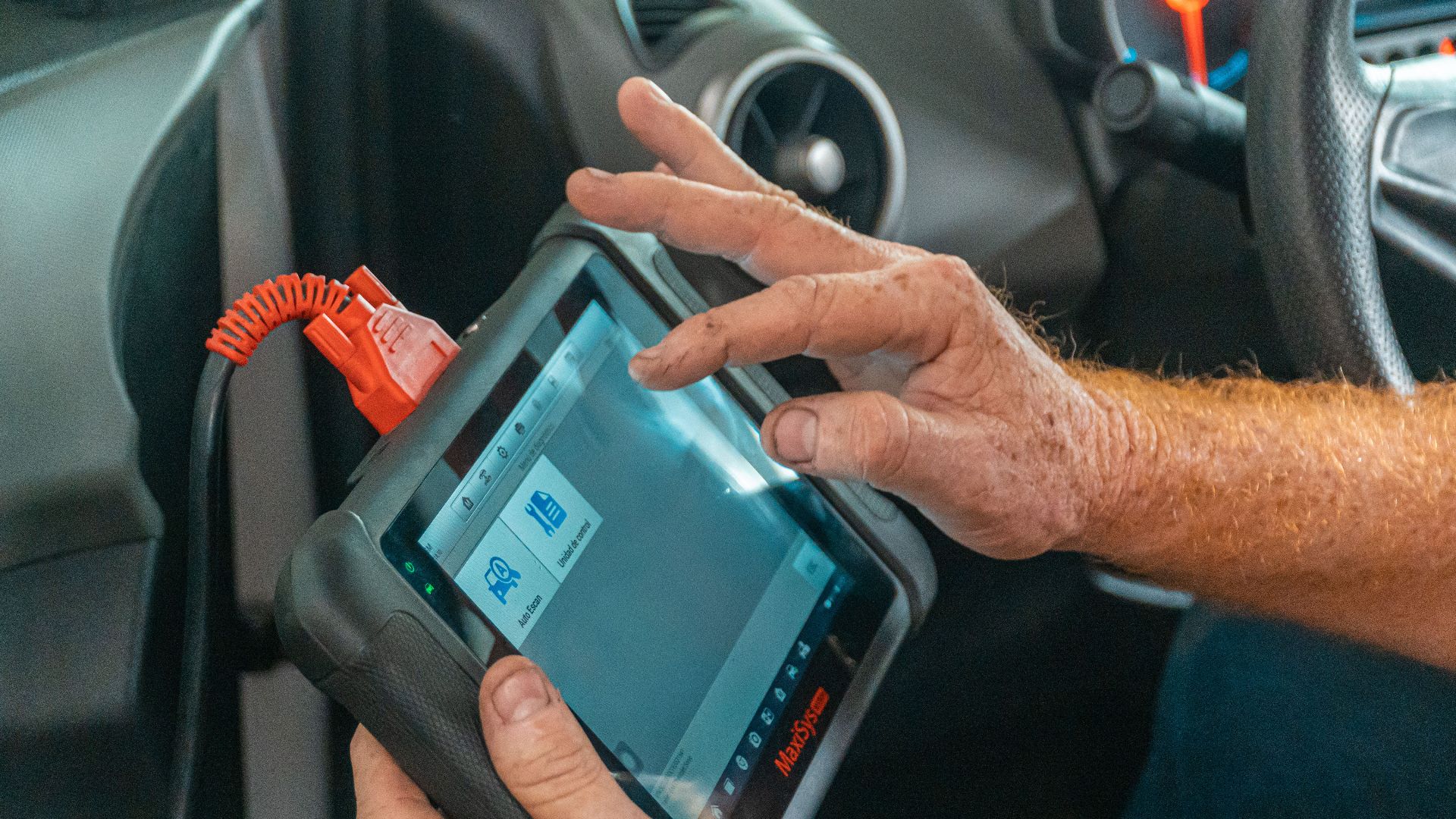 Mechanic using a diagnostic tool inside a car to check for engine issues and ensure proper maintenance.