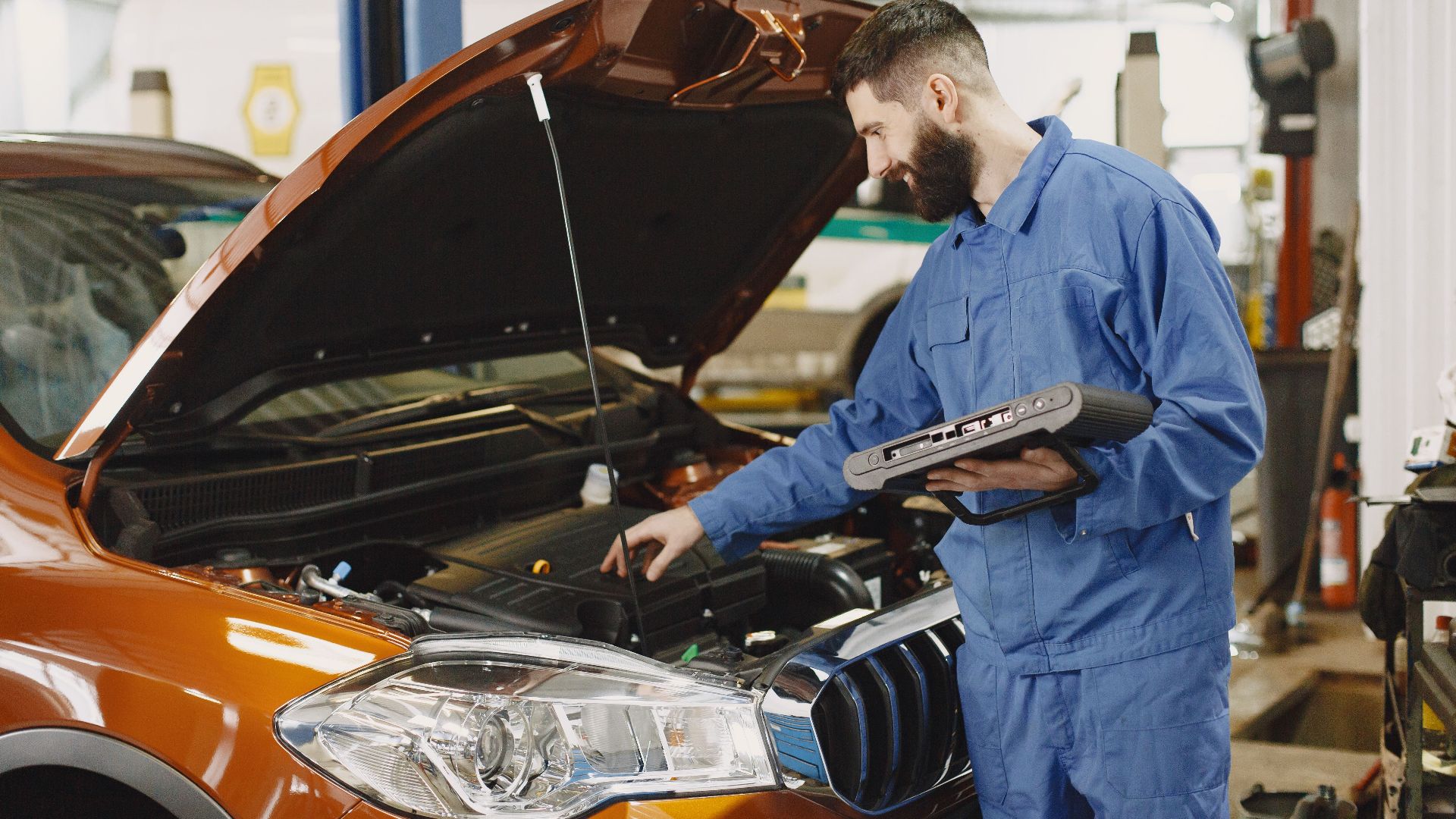 Skilled mechanic working on car engine diagnostics in a modern garage.
