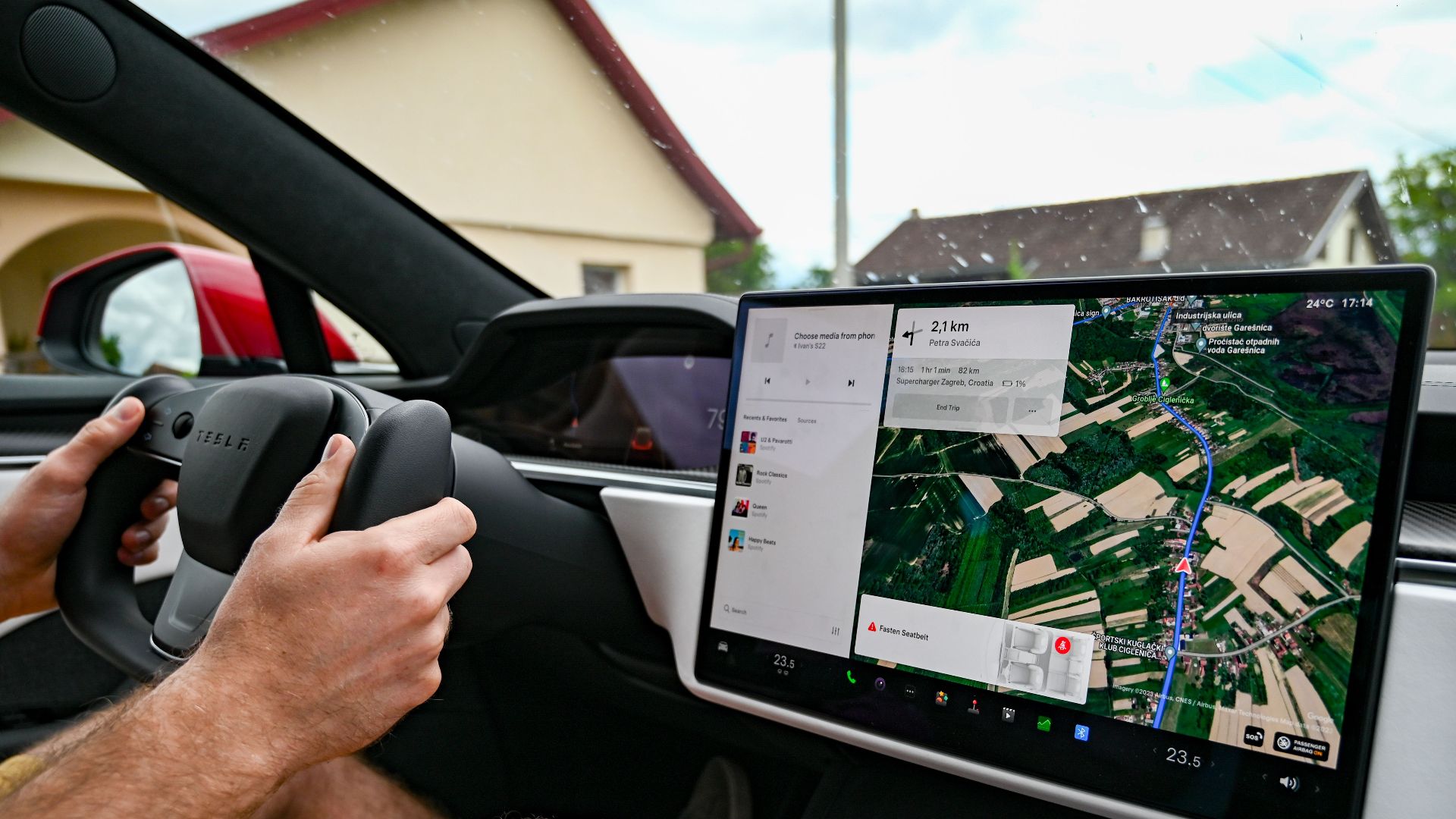 Man driving Tesla using GPS on touchscreen dashboard for navigation.