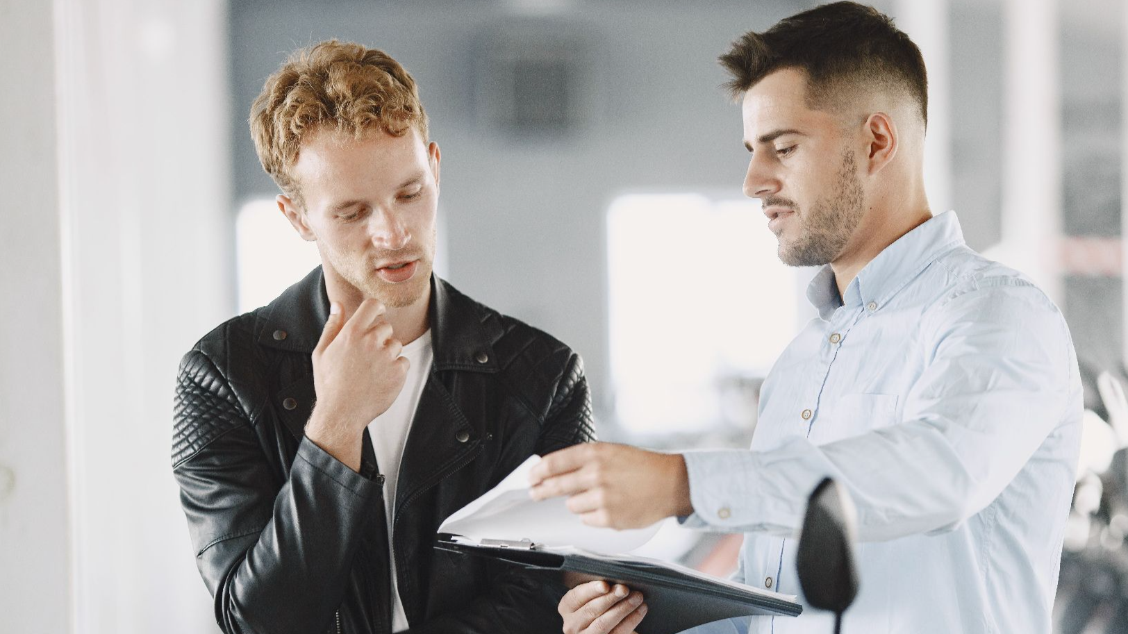 Two adults discussing purchasing options at a motorcycle dealership.