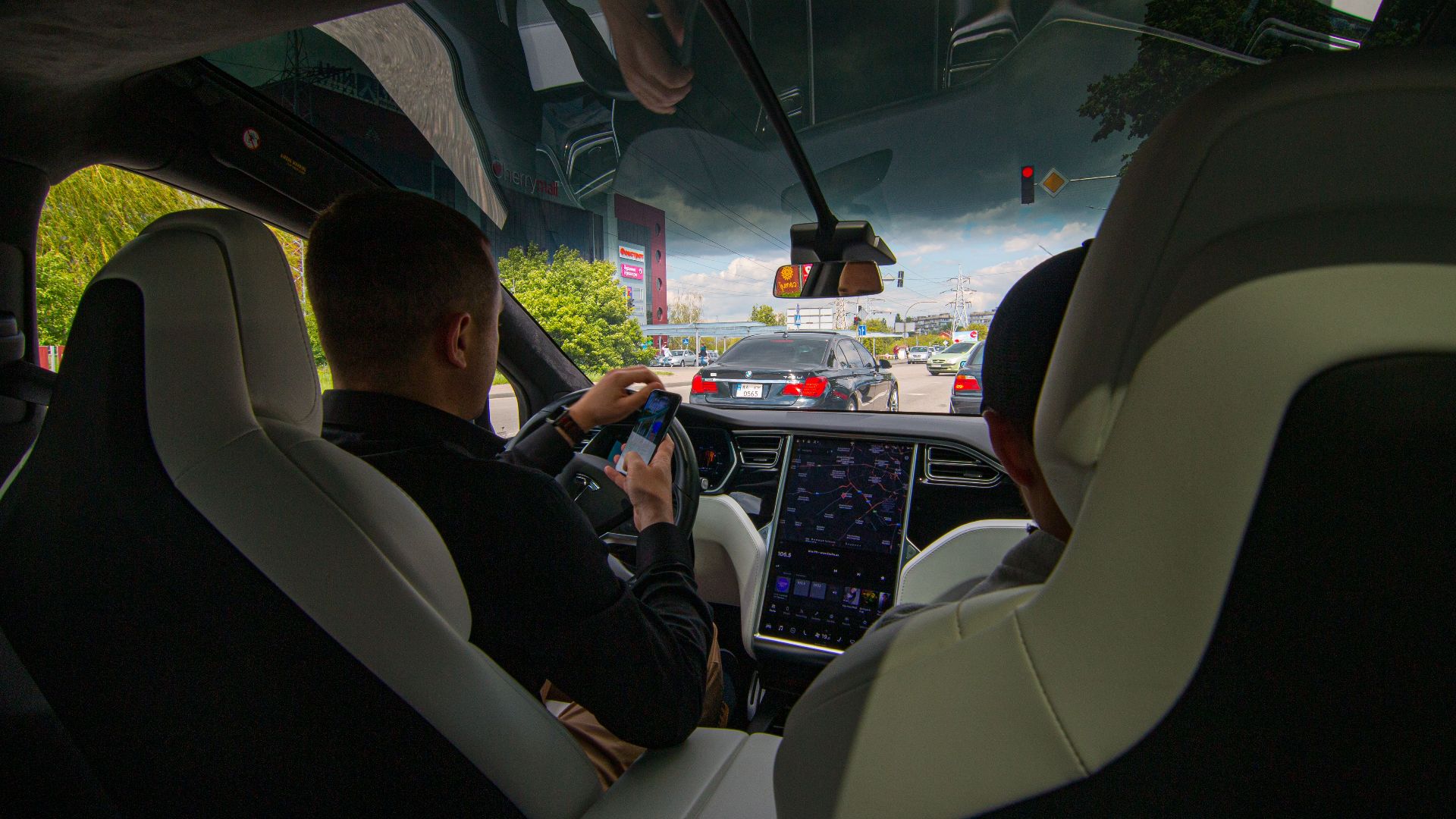 Inside a Tesla vehicle in city traffic, showcasing modern technology and urban driving.