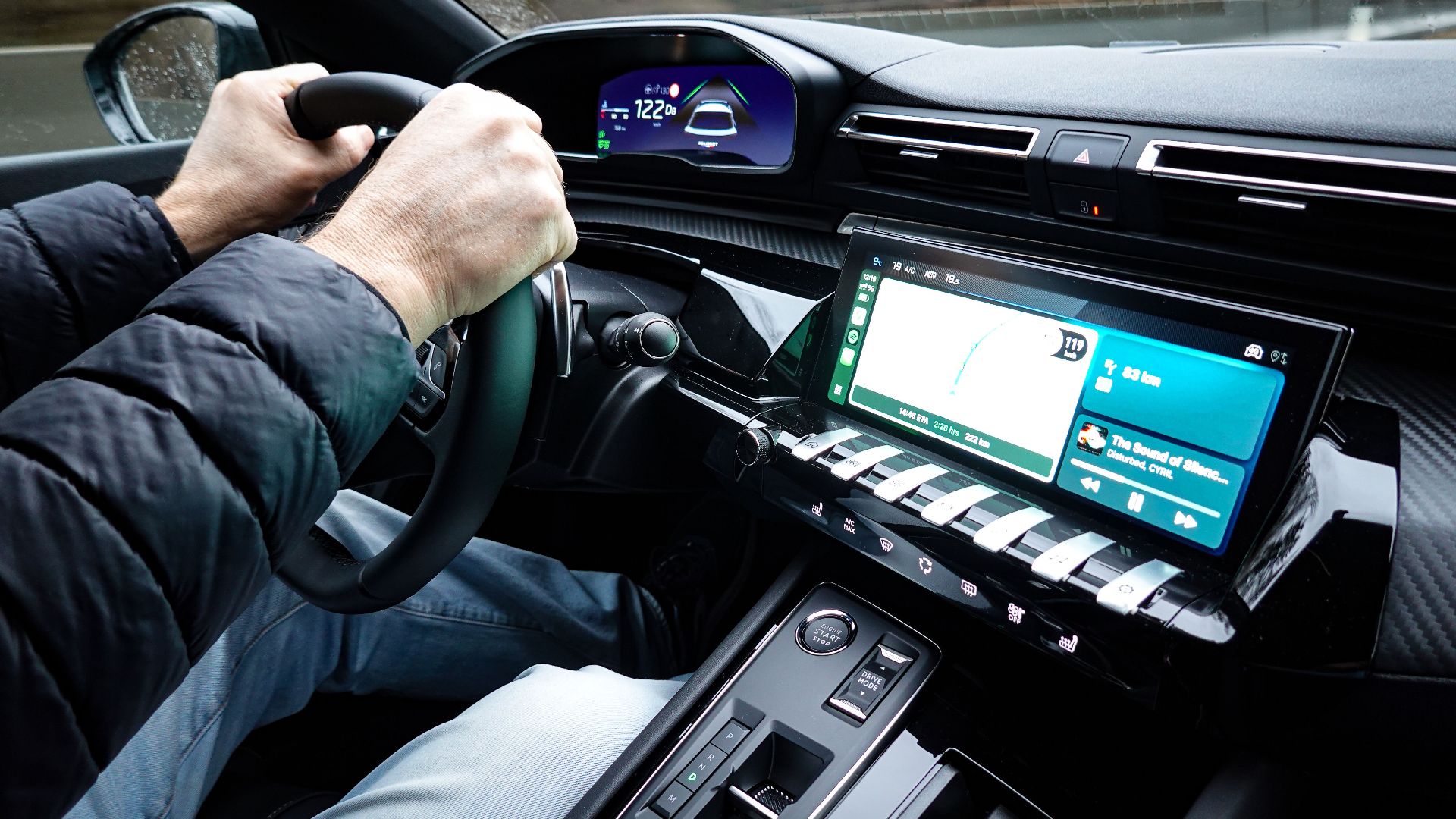 A detailed view of a car's interior with hands on the steering wheel, showcasing modern technology.
