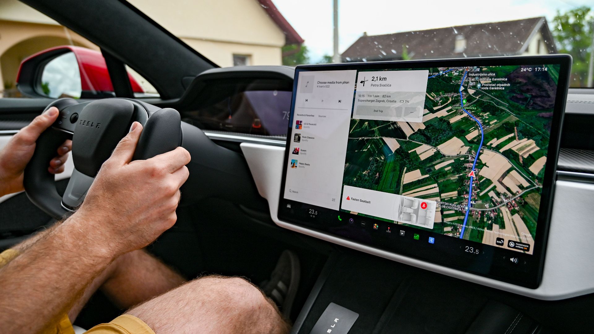 Man driving Tesla using GPS on touchscreen dashboard for navigation.