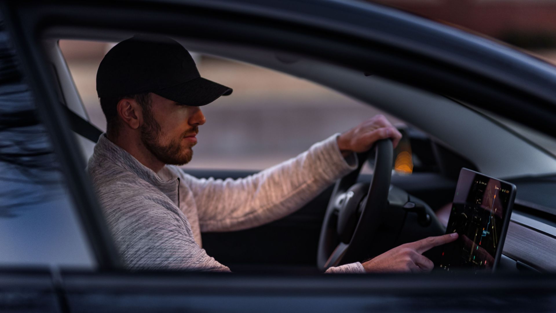 A man interacts with a touchscreen inside an electric car, driving through Dallas, TX.