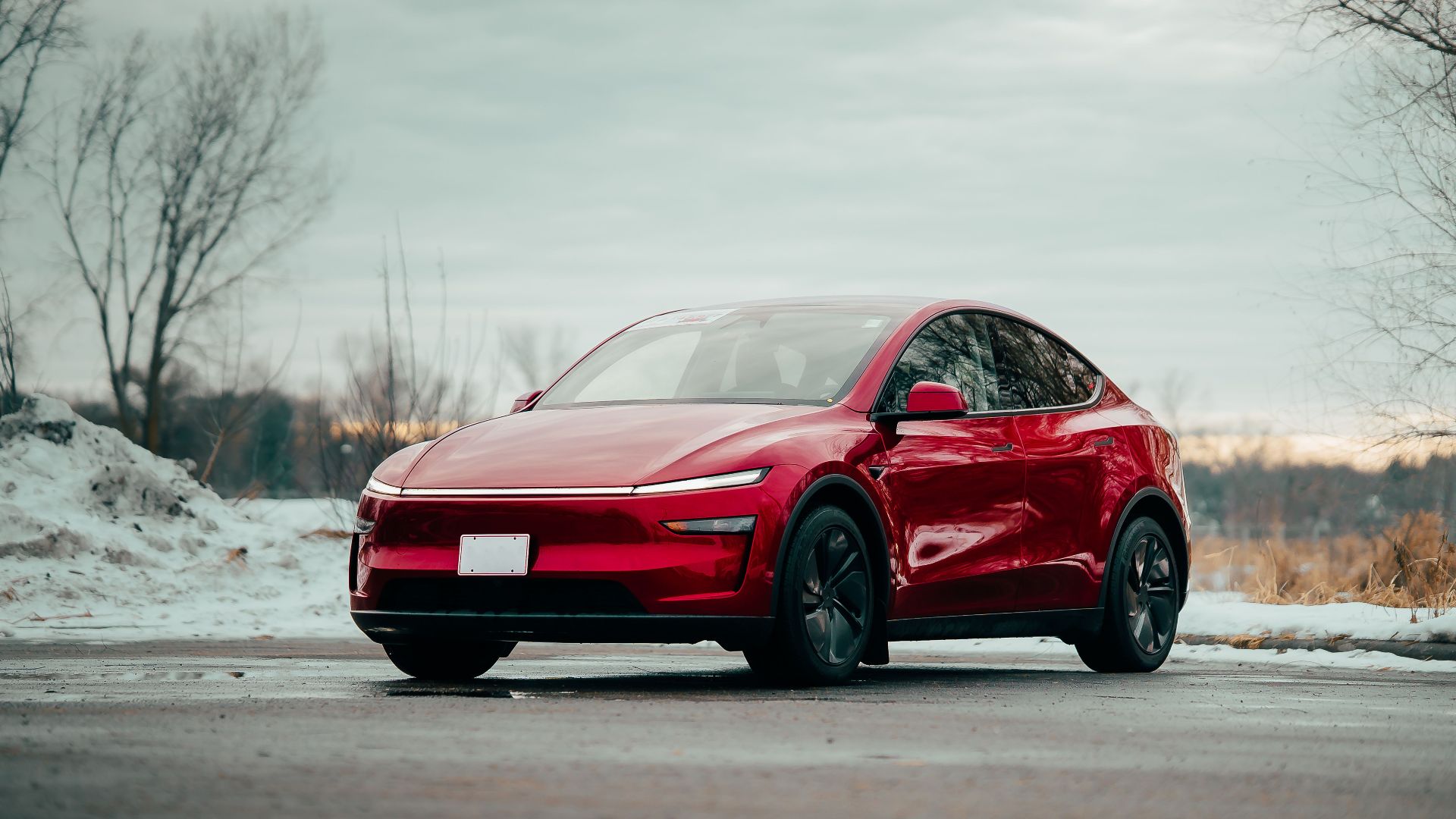 Red electric car parked outdoors, showcasing sleek design amidst winter scenery.