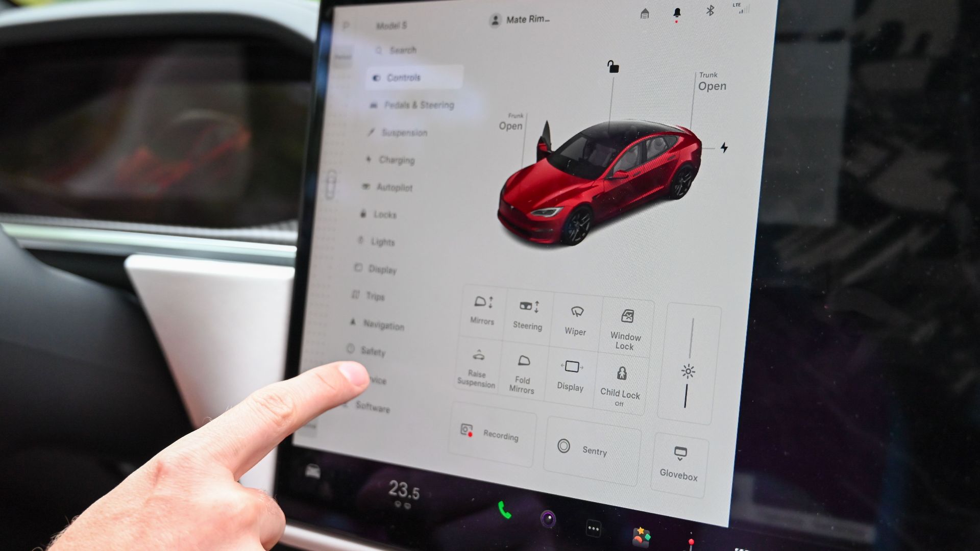 Close-up of a hand interacting with a modern car's touchscreen interface for various controls.
