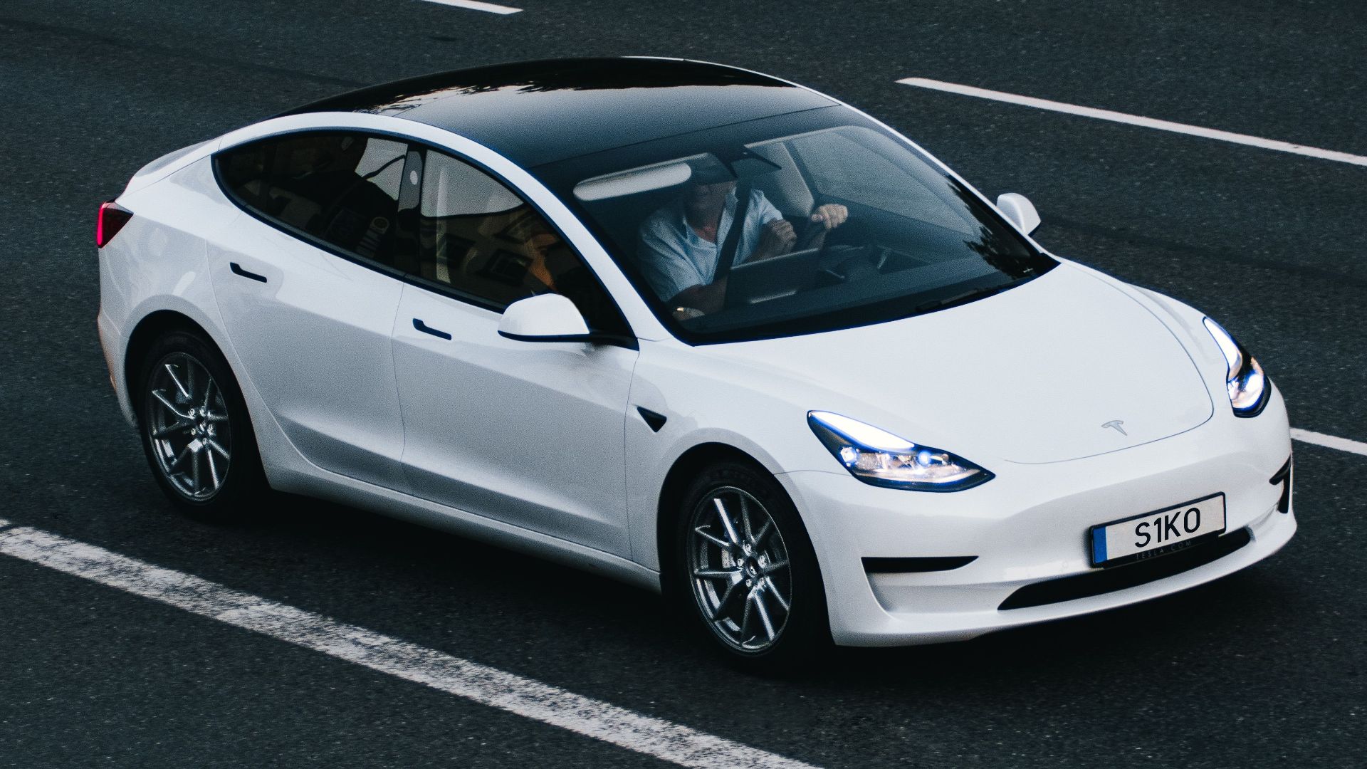 Tesla Model 3 driving on a highway in Osnabrück, Germany, showcasing modern electric vehicle design.
