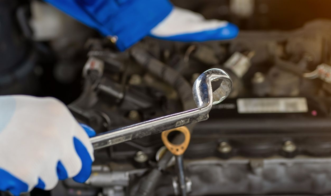 Close-up view of auto mechanic working on car engine in garage. Repair service