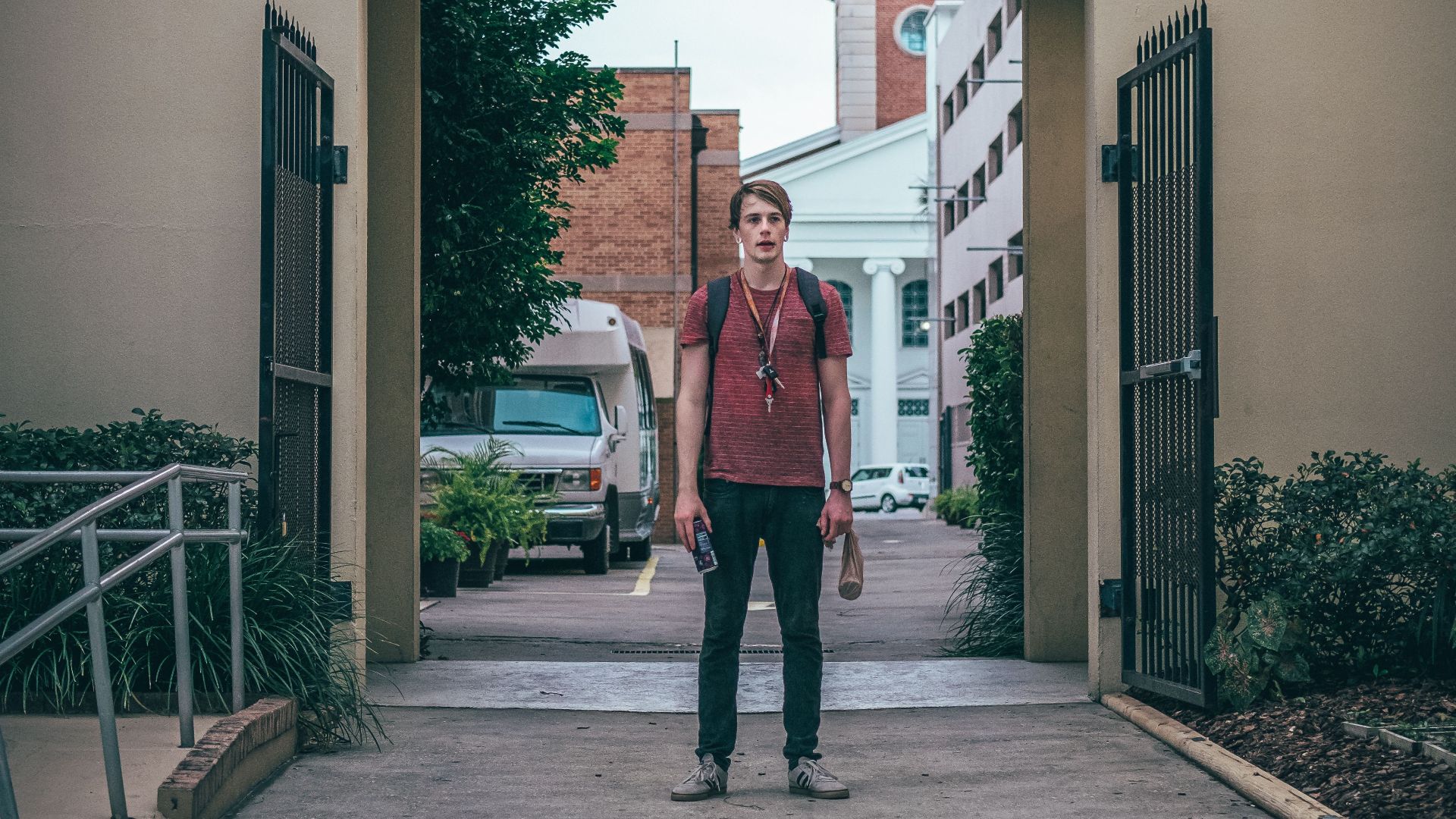 Man standing under an archway marked 'EXIT' with an urban backdrop.