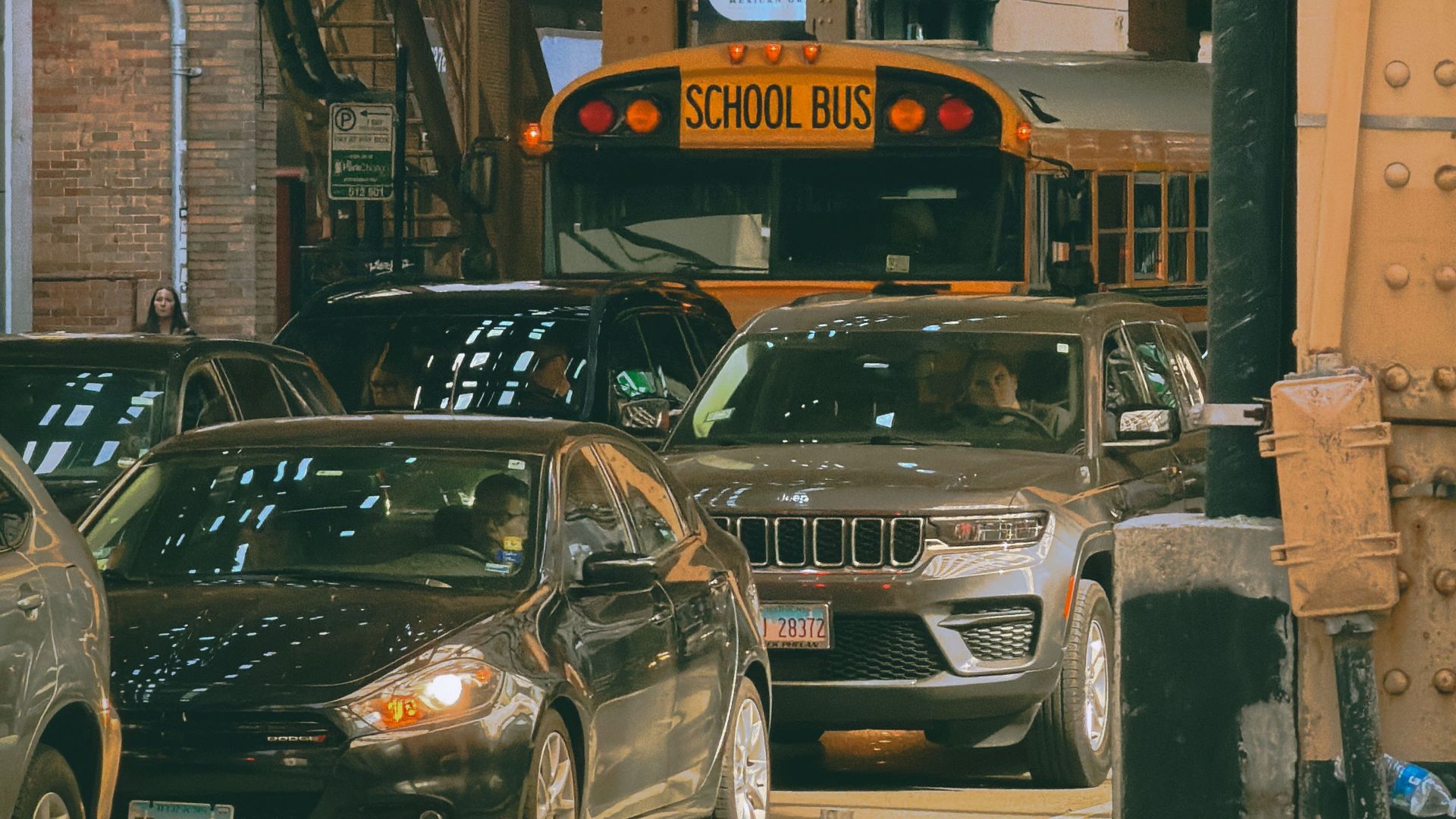 Busy Chicago traffic under iconic elevated train tracks with cars and a school bus.