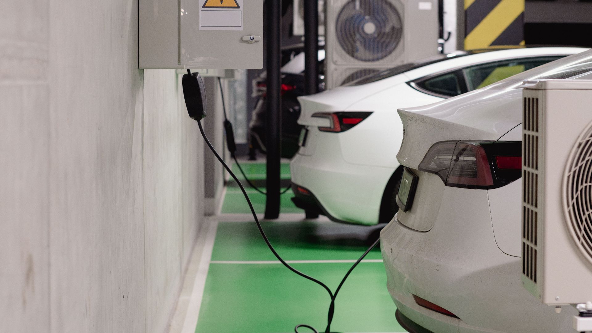 Electric vehicles charging at an indoor station in a modern underground garage.