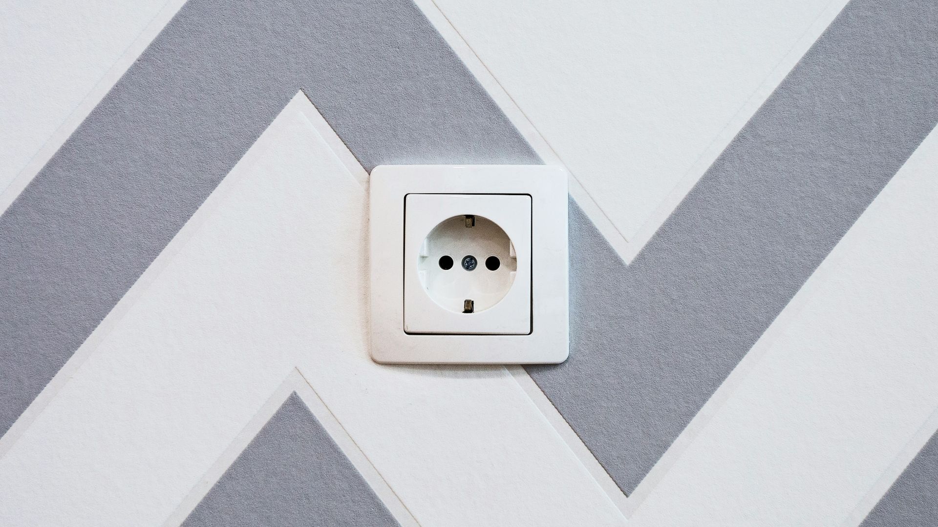 white power strip mounted on white and grey chevron painted wall