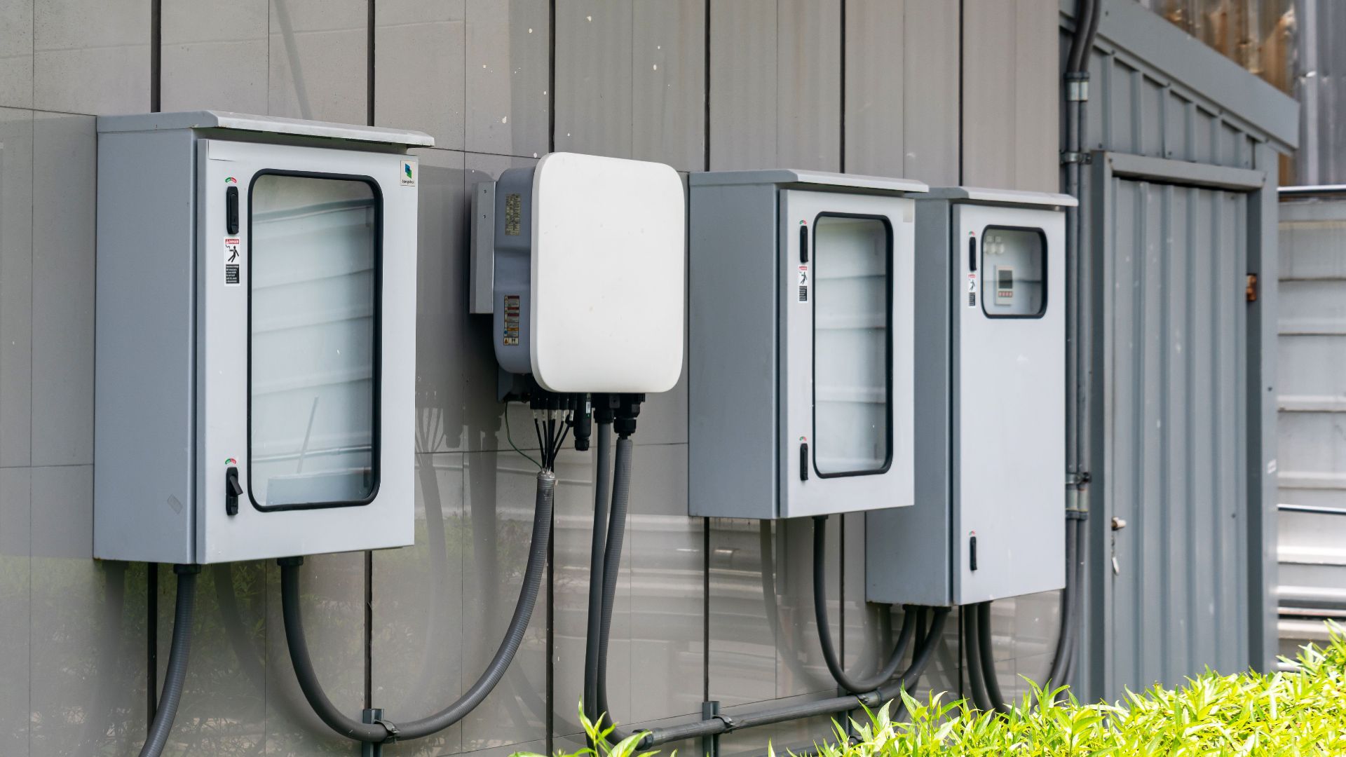 Close-up of outdoor electrical utility boxes with cabling on a building exterior.