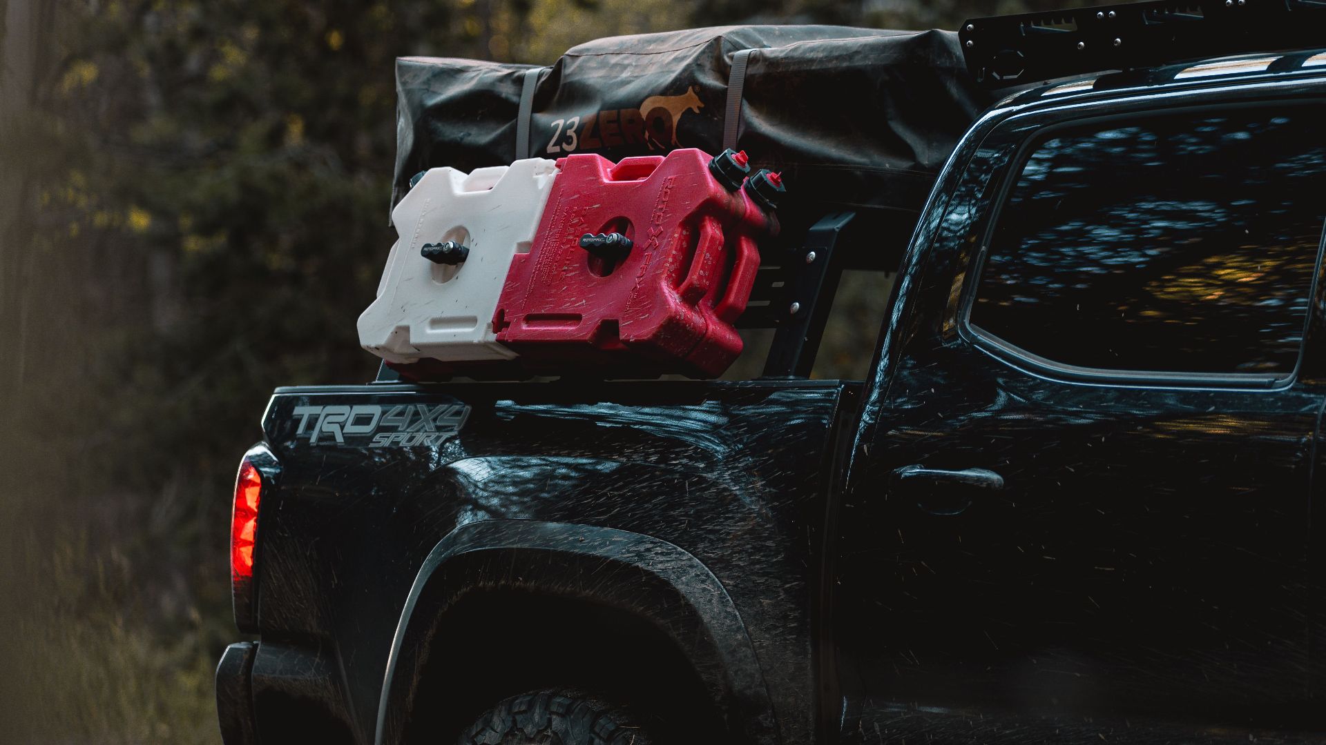 A rugged off-road pickup truck carrying gas containers on a wooded path, perfect for adventure.
