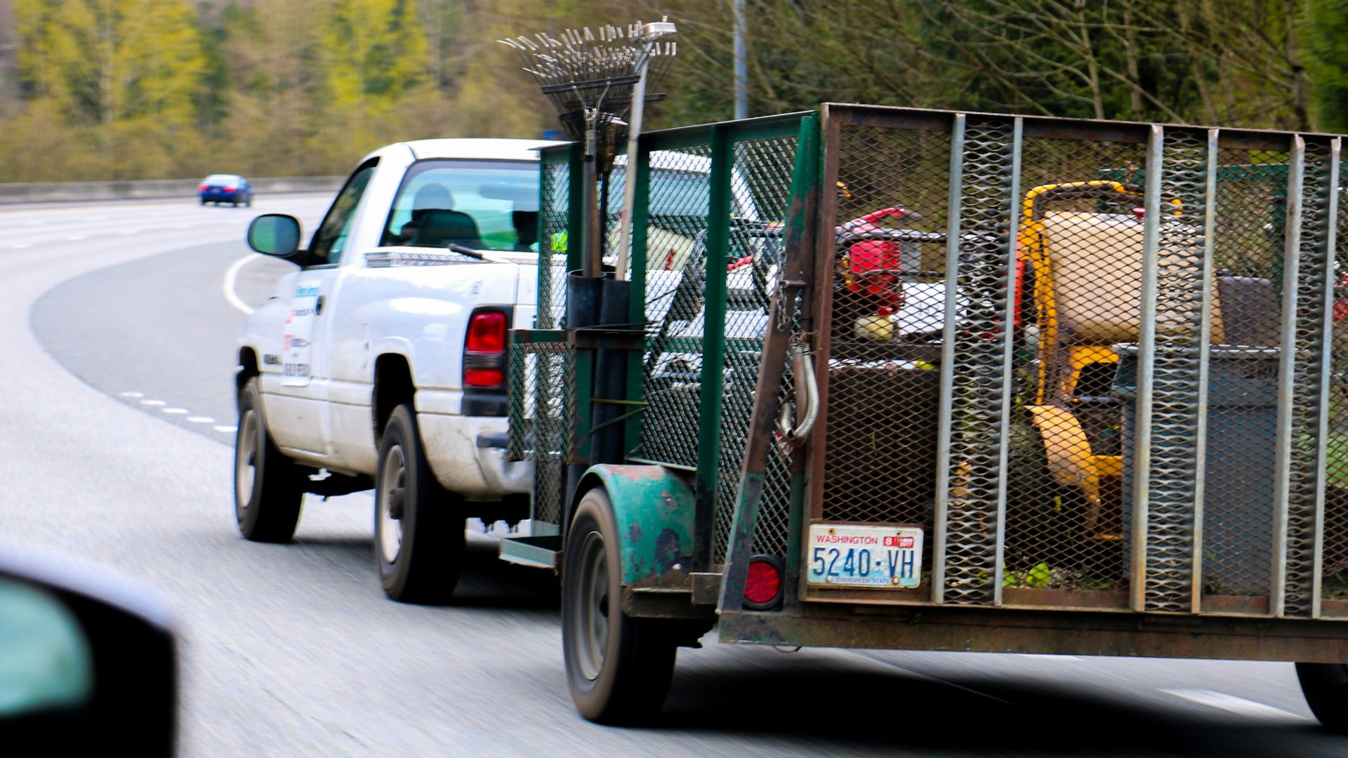 a white truck driving down a road next to a forest