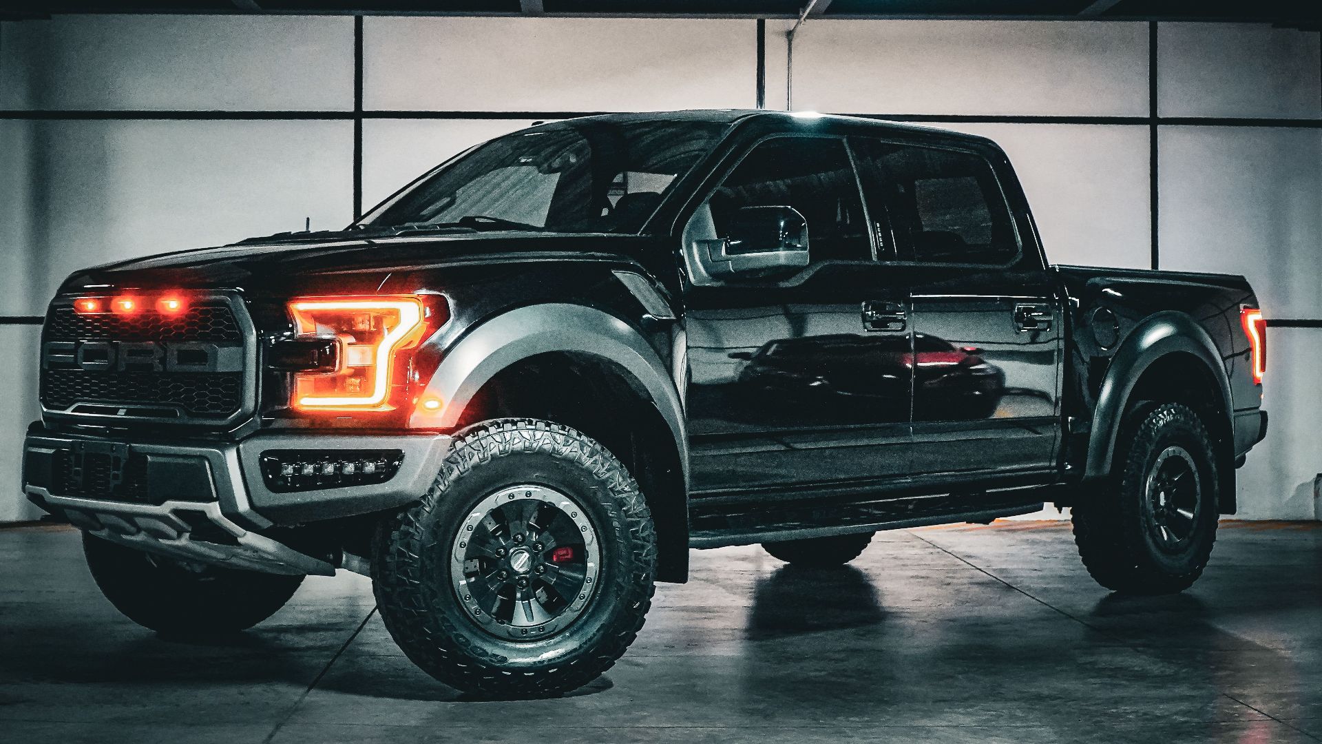 Bold black pickup truck with illuminated lights in an industrial garage.