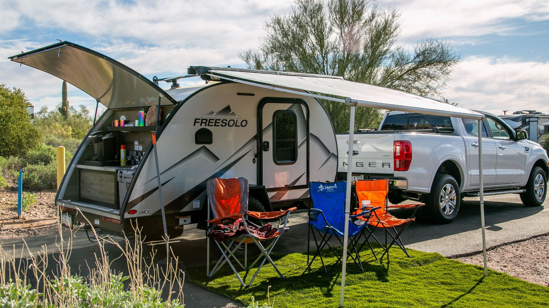 A scenic campsite in Apache Junction, AZ showcasing a Freesolo motorhome with camping chairs and pickup truck.