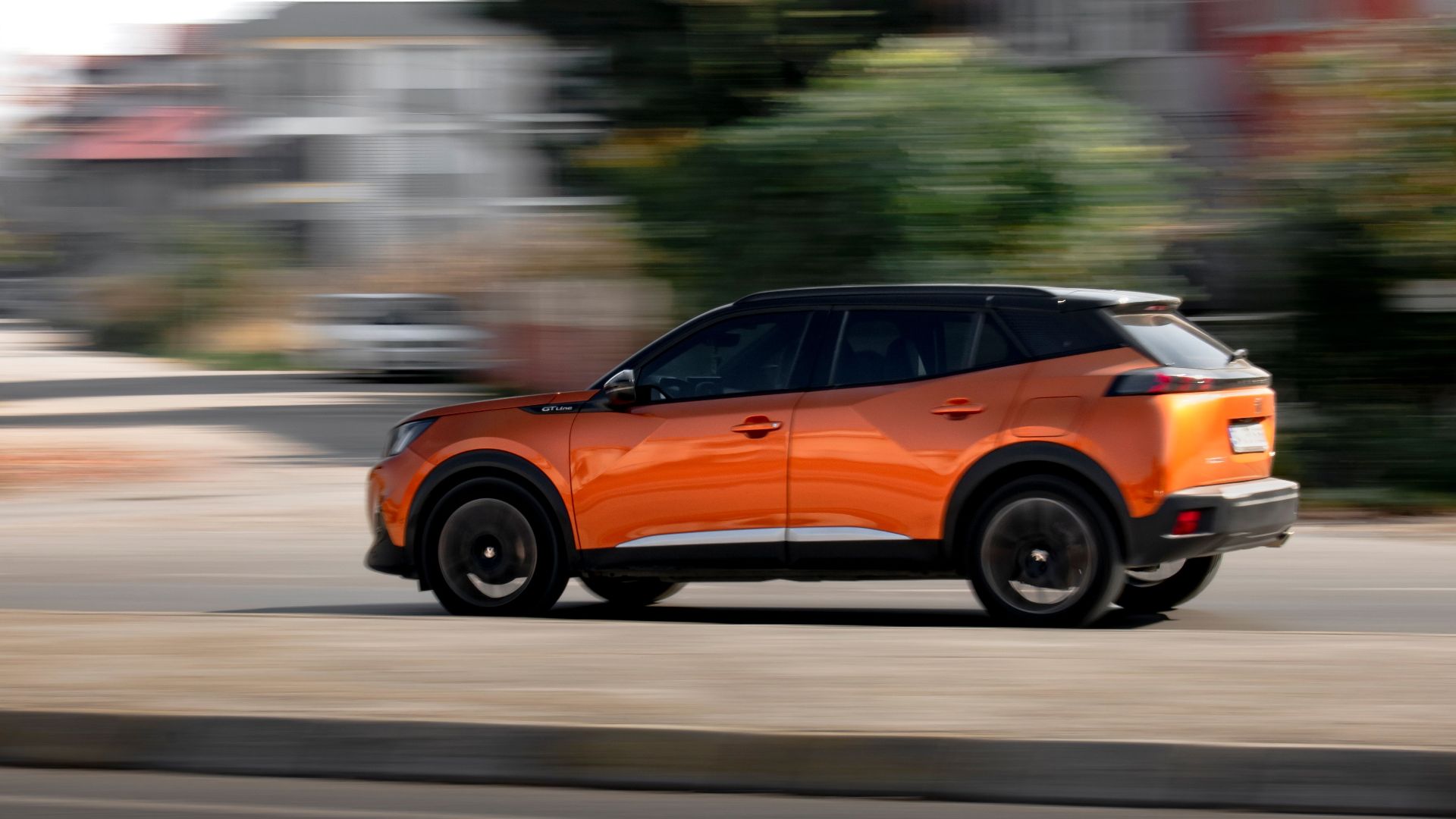 Orange SUV driving fast on an urban road, showcasing motion blur and speed.