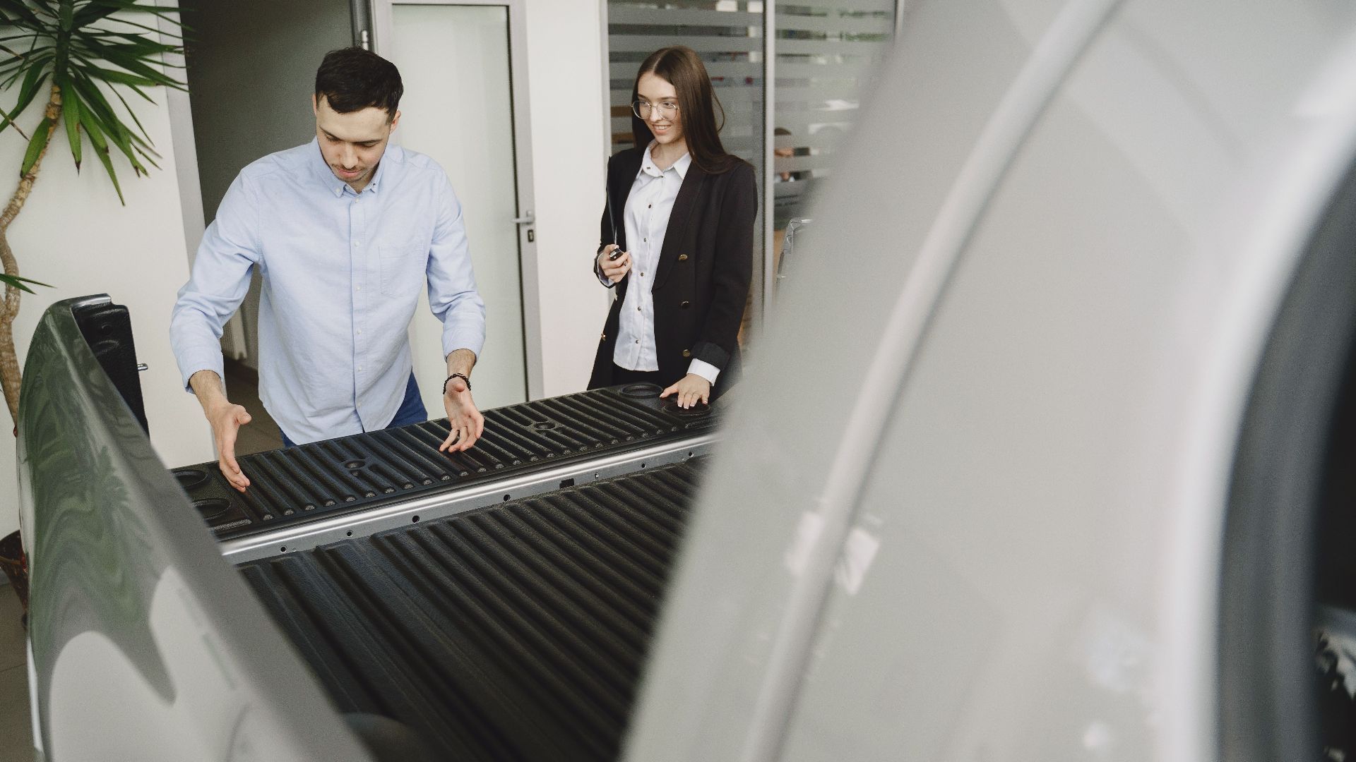 Salesman and client inspecting a pickup truck in a car dealership, discussing features.