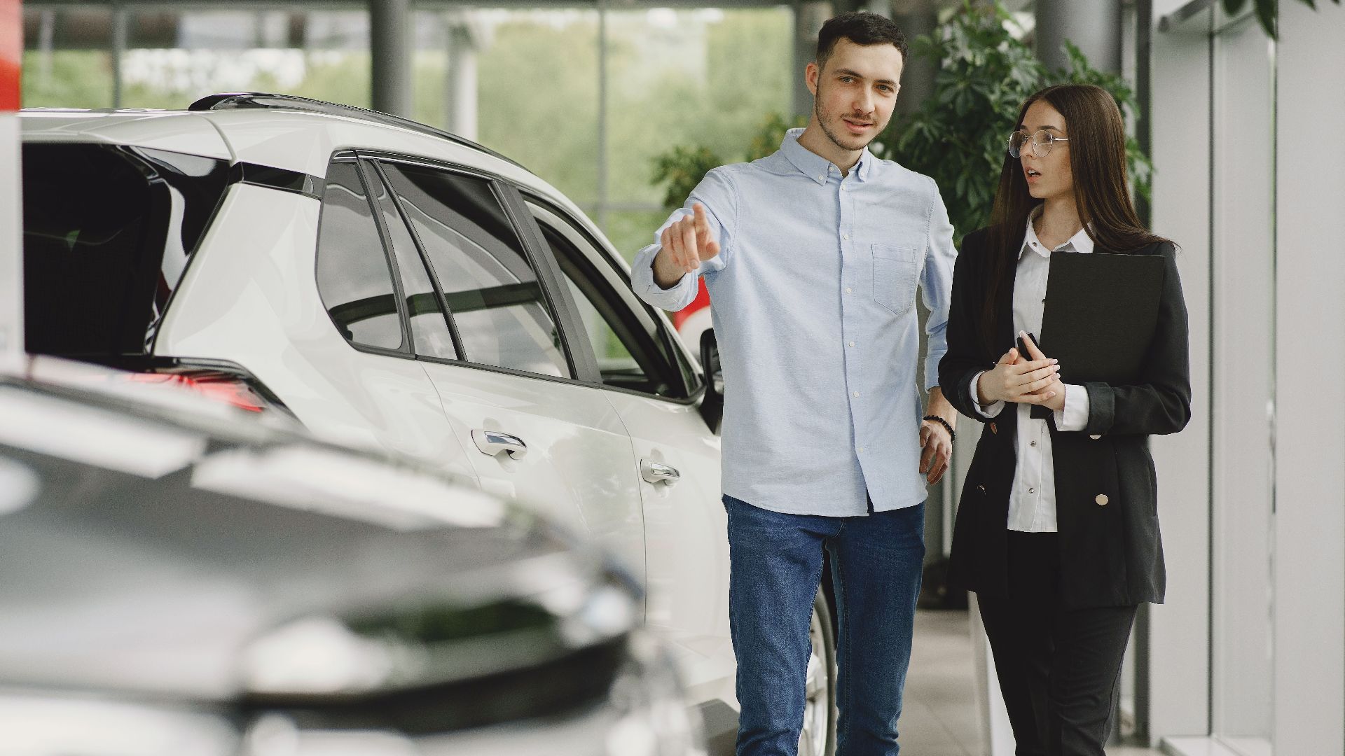 Customer and salesperson discussing a vehicle inside a modern car dealership showroom.