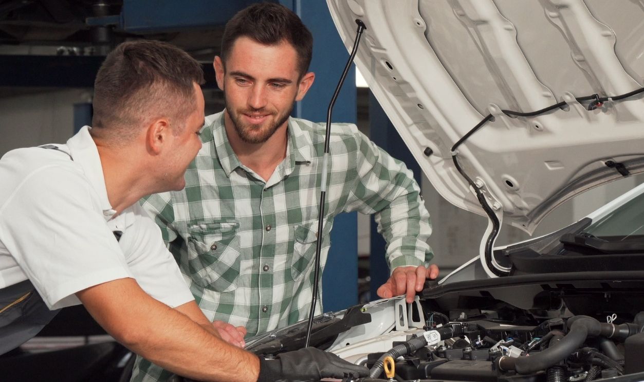Shutterstock-1250630776, Car service mechanic repairing automobile while talking to the customer