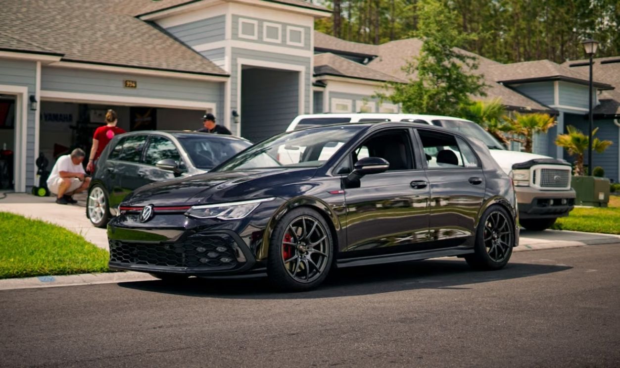 A modern suburban neighborhood featuring a stylish car parked on a driveway.