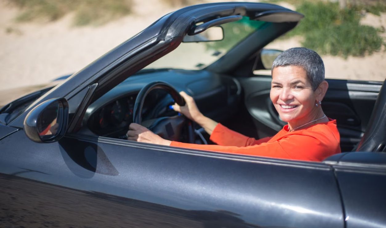 Confident woman enjoying a drive in her luxury convertible outdoors, embracing freedom and joy.