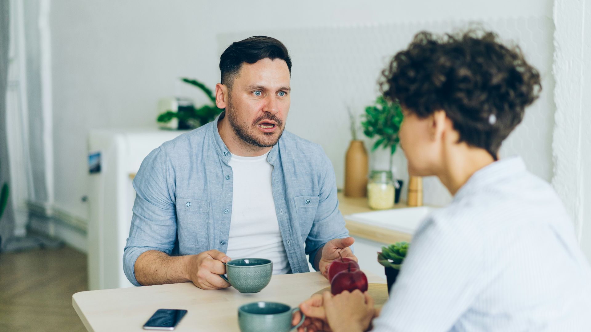 a man sitting at a table talking to a woman