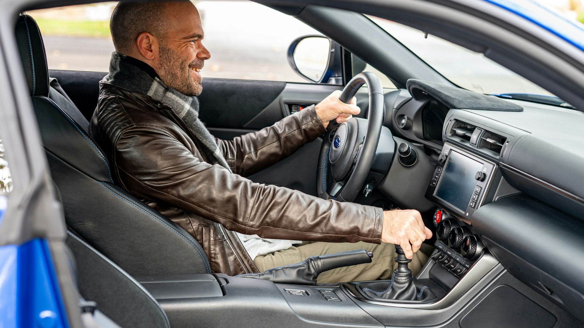 A man sitting in a car with a steering wheel