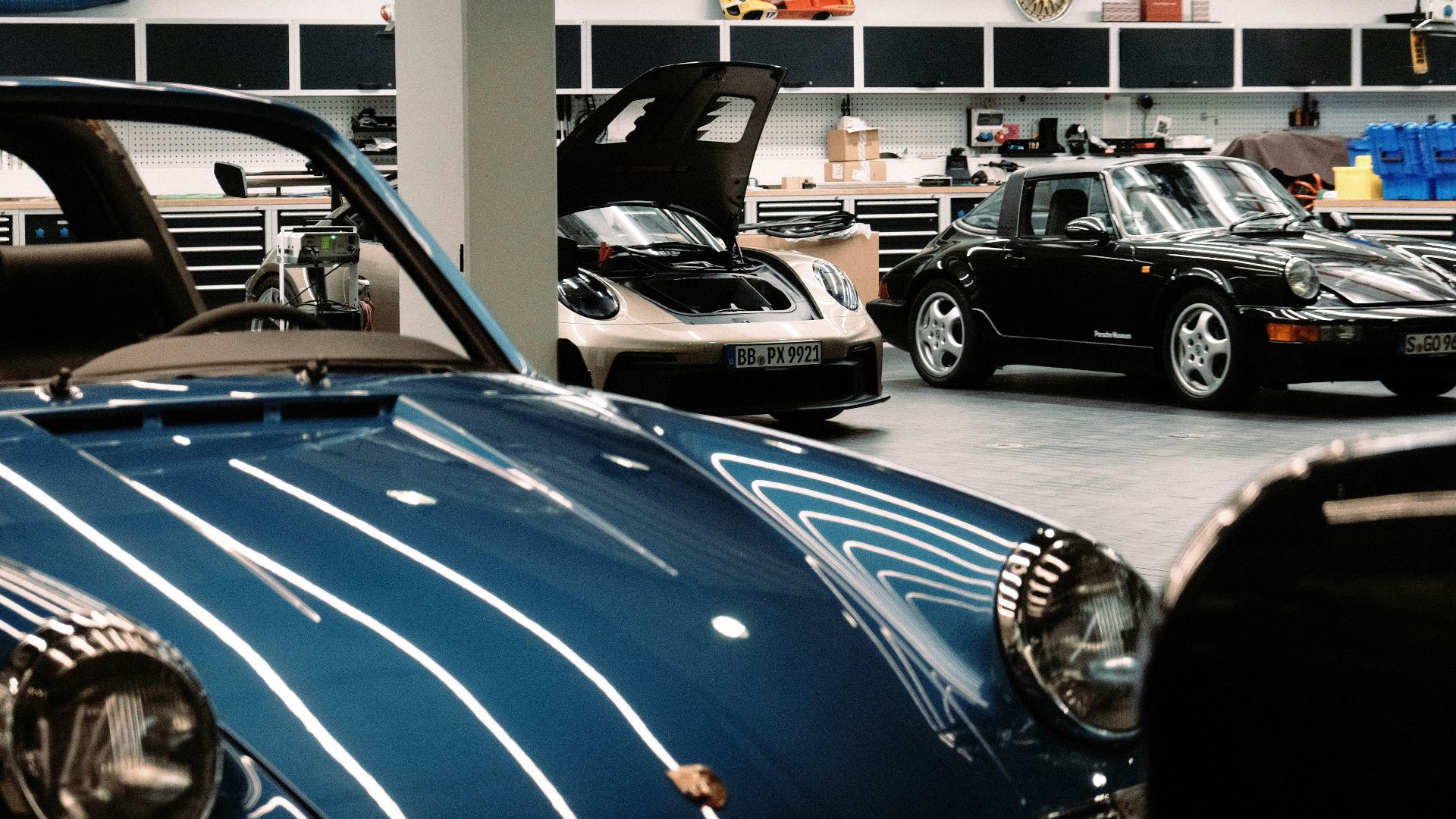 Classic cars parked inside a pristine automotive workshop.