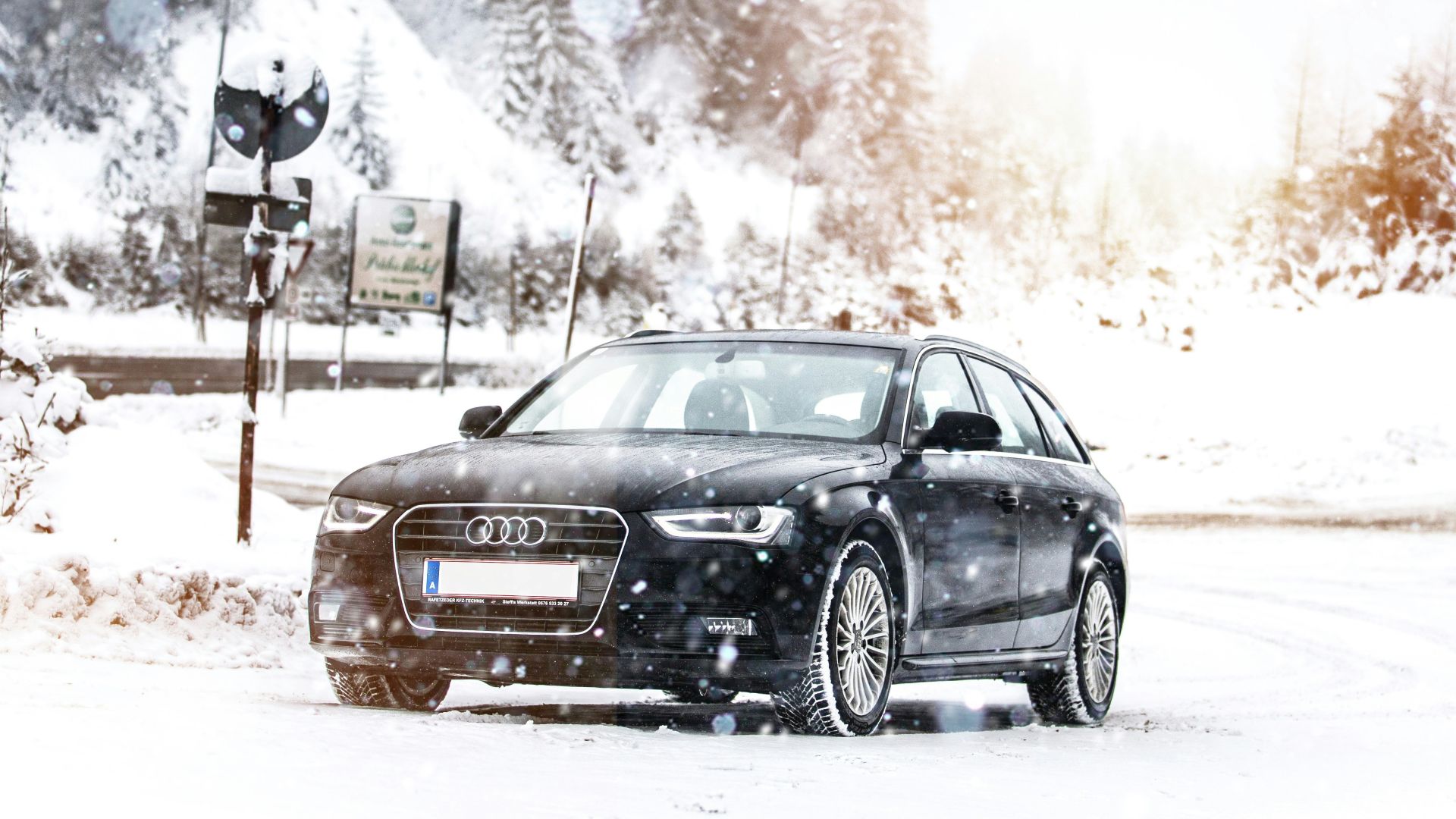 a black car driving down a snow covered road